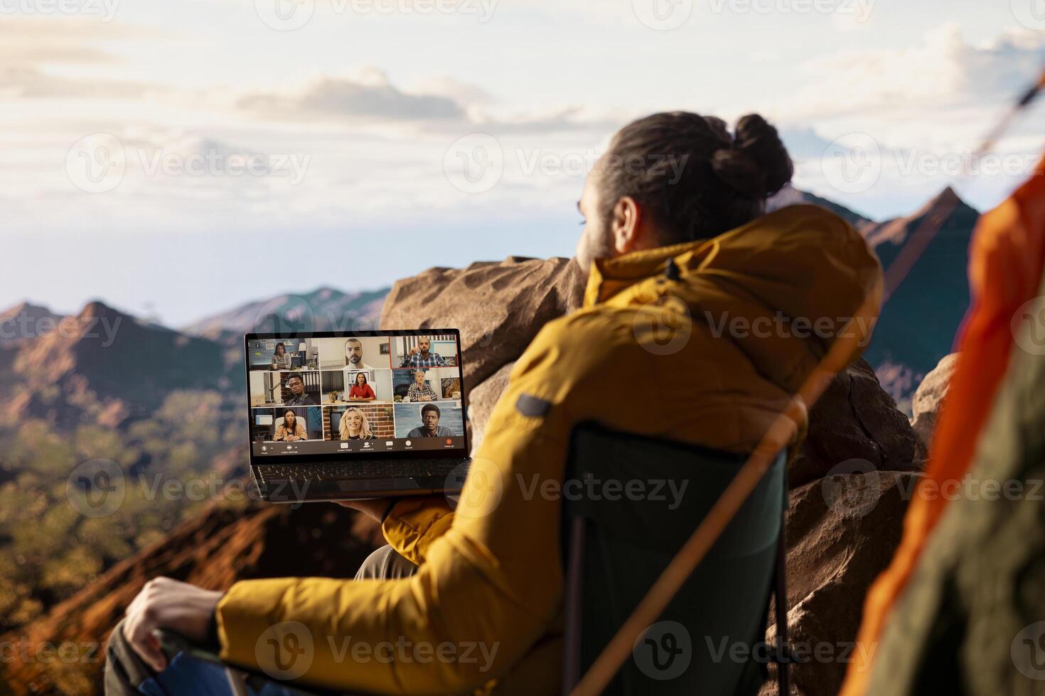 Business employee uses high speed internet connection on mountain top, enjoying the call with a scenic landscape. Male hiker with an internet dependency being workaholic. photo