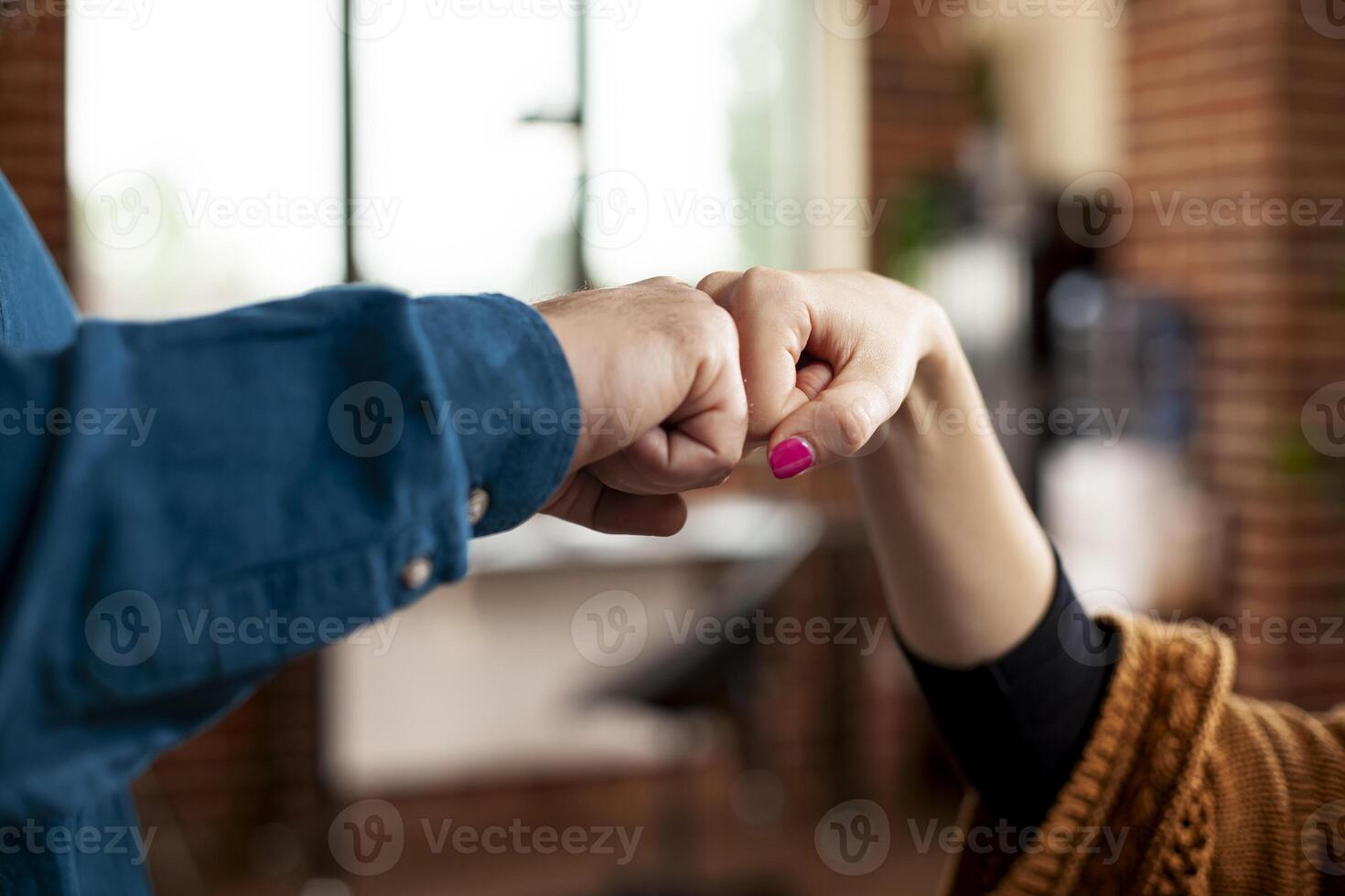 Closeup of hands exchanging fist bump in office, symbolizing unity and cooperation between partners. Two professional individuals making hand gestures, representing successful business collaboration. photo
