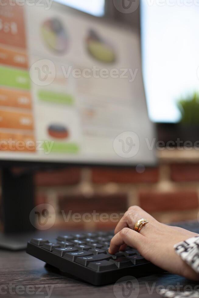 Focused shot of fingers on a keyboard, inputting company data in a brick wall workplace. Closeup of hands typing at a startup office desk, entering project details on a digital device. photo