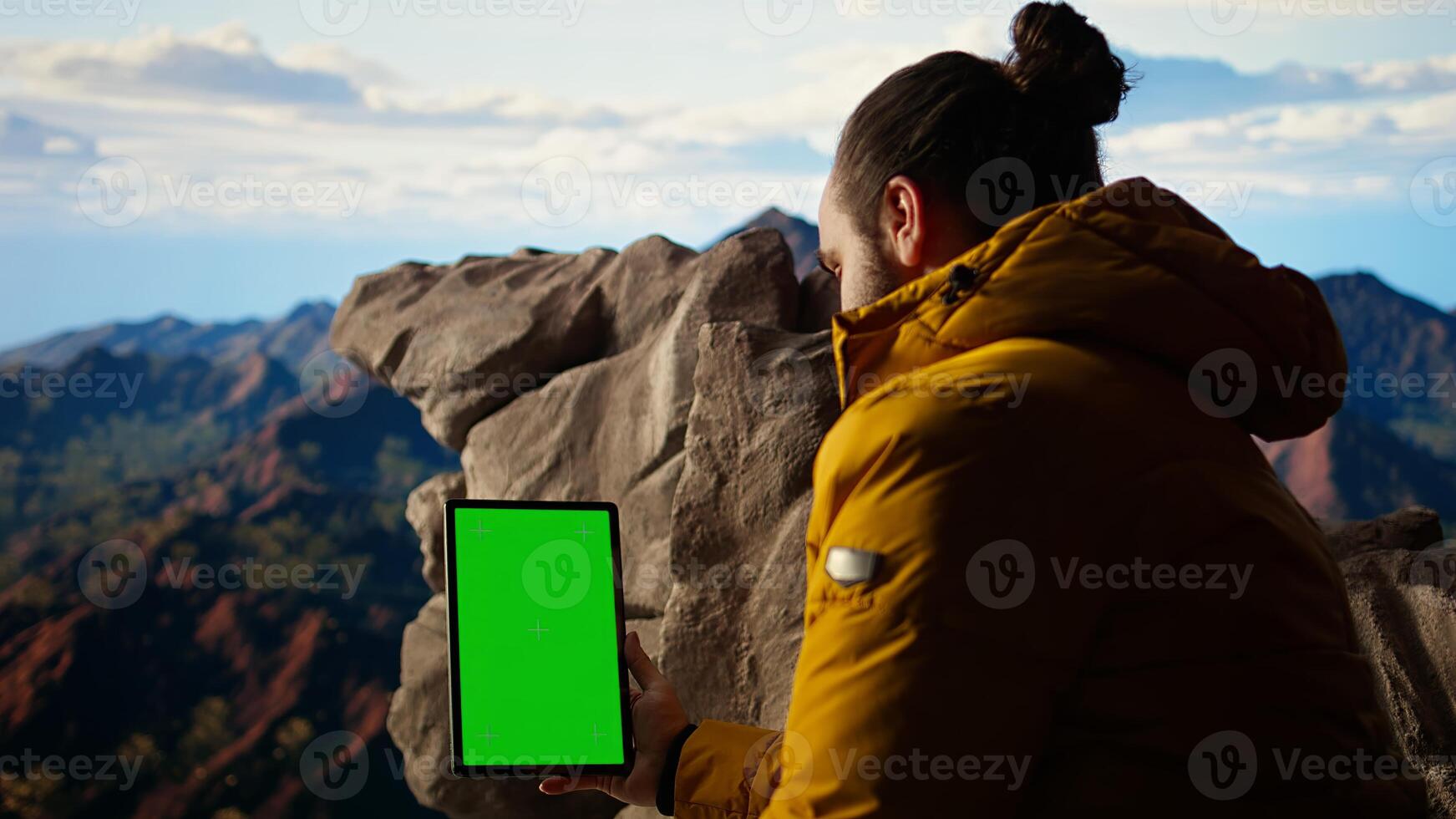 Mountaineer stands at the peak with satisfaction and uses mockup screen, hiker admires breathtaking view with crisp air on mountain top. Scenic surroundings highlights determination. Camera A. photo