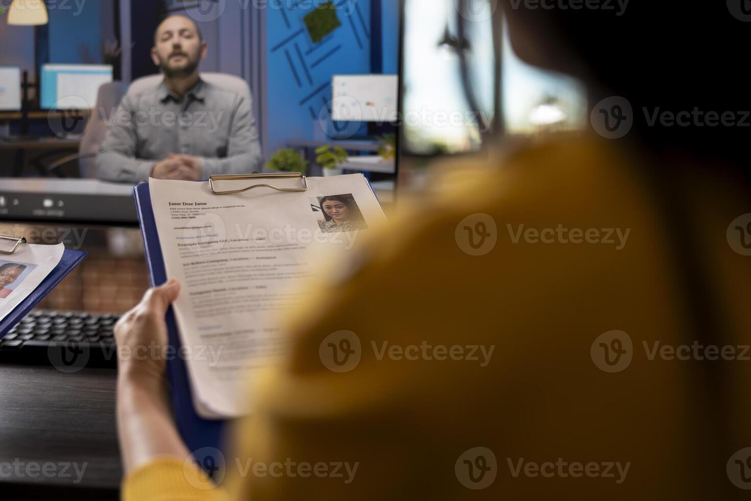 Closeup of resume of a job candidate being reviewed by someone during virtual meeting with manager. Selective focus on CV of female applicant, held by a person attending videoconference with HR staff. photo