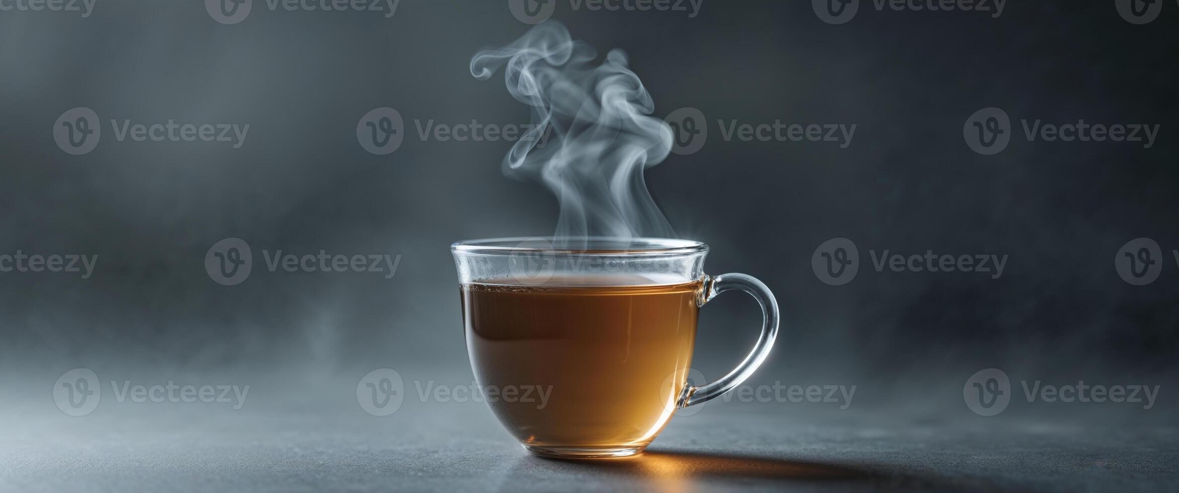 A glass cup of tea with steam rising from it photo