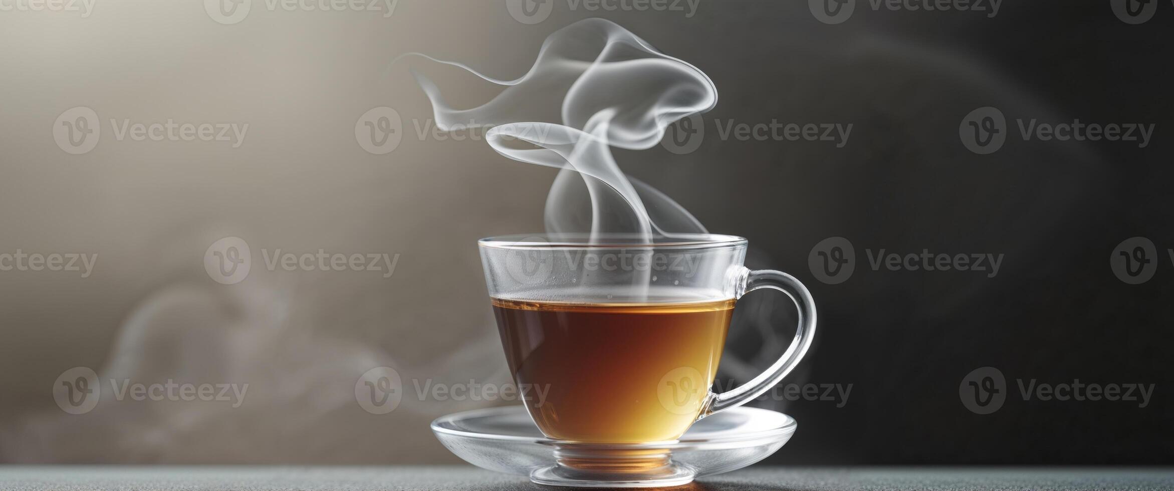Hot Tea in Glass Cup with Steam Rising on Dark Background. photo