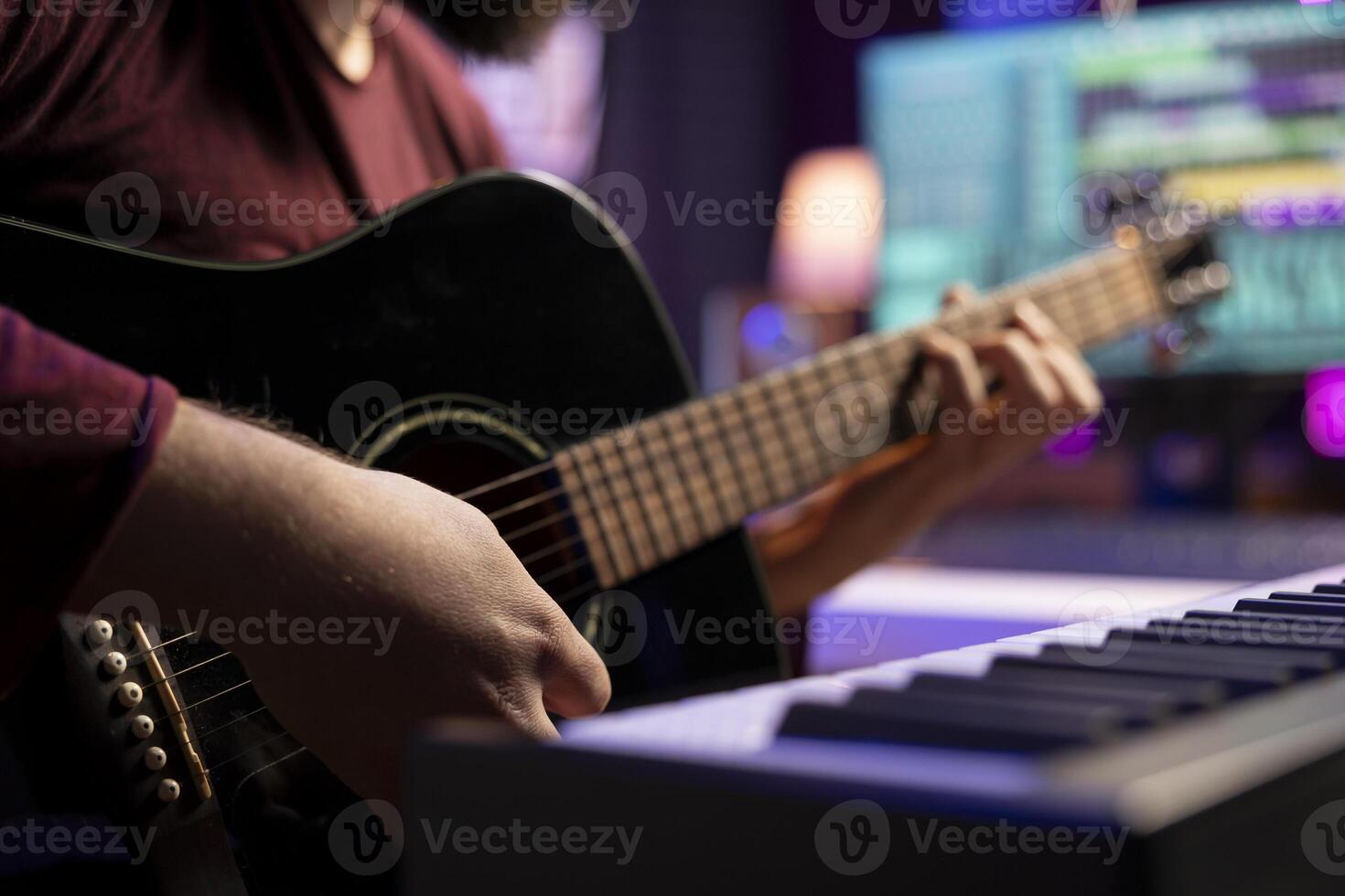Young artist playing guitar and creating music using daw software interface on computer, recording audio files. Musician composing songs in home studio and mixing acoustic sounds. Close up. photo