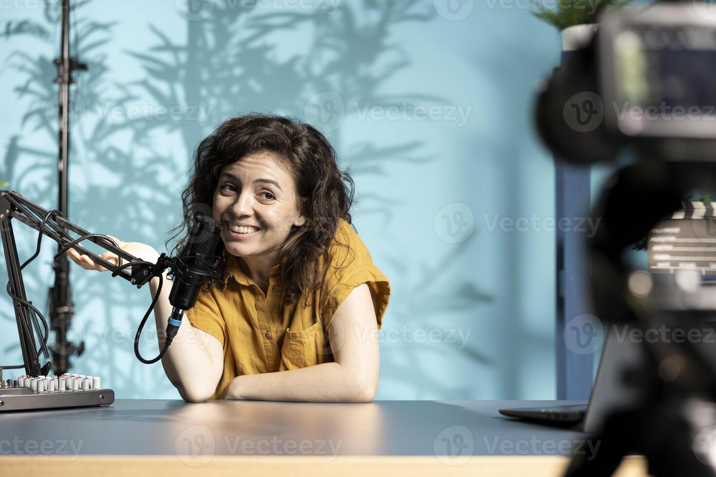 Joyous woman filming vlog with high tech gear in professional studio, speaking into microphone equipment. Happy influencer talking to subscribers about trending topics on online channel photo