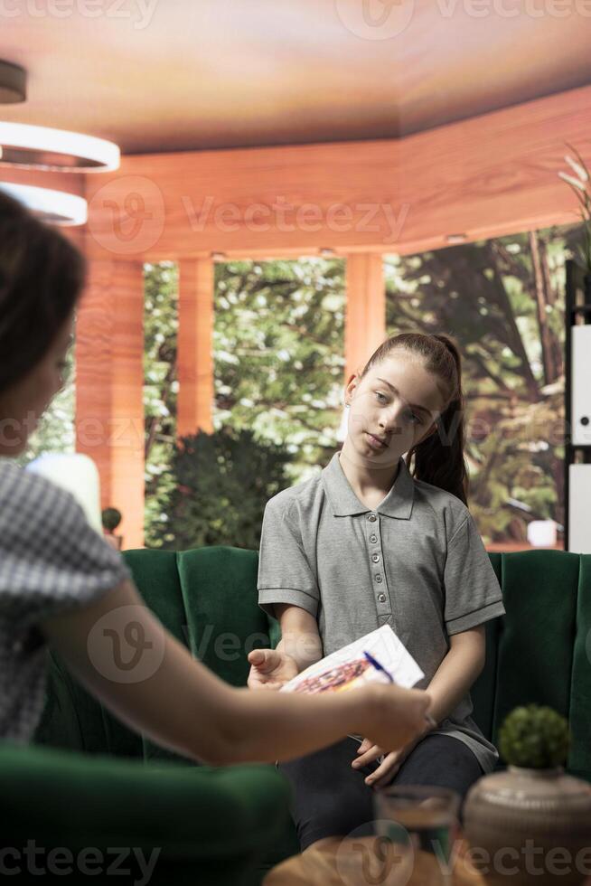 Therapist studies ominous gory drawings from a troubled teen, doing a psychoanalysis at therapy session. The dark sketches depict disturbing violent behavior, unsettling danger signs. photo
