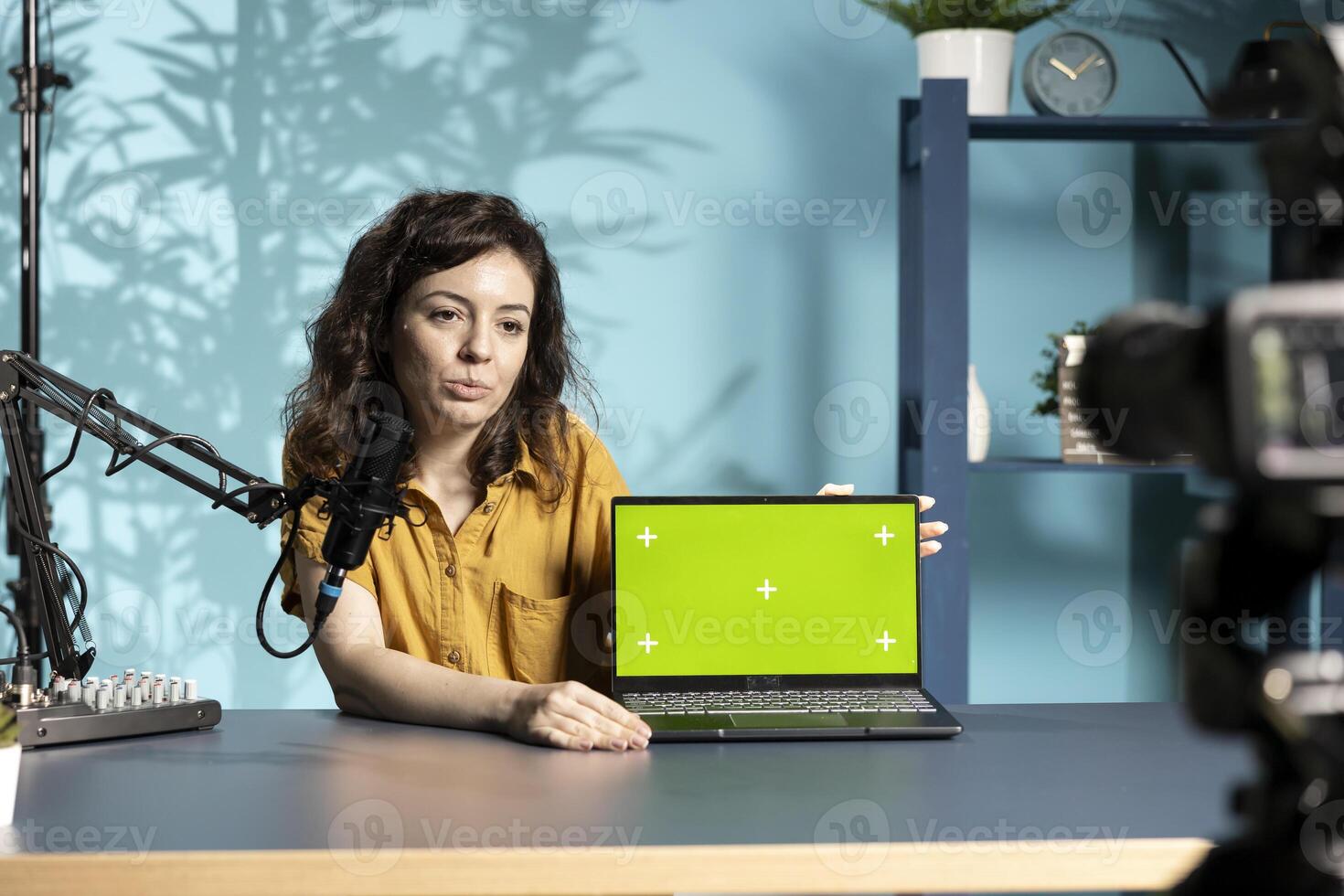 Influencer talking to audience about recent news headlines, reading from chroma key laptop. Woman discussing with subscribers, presenting information from green screen notebook photo