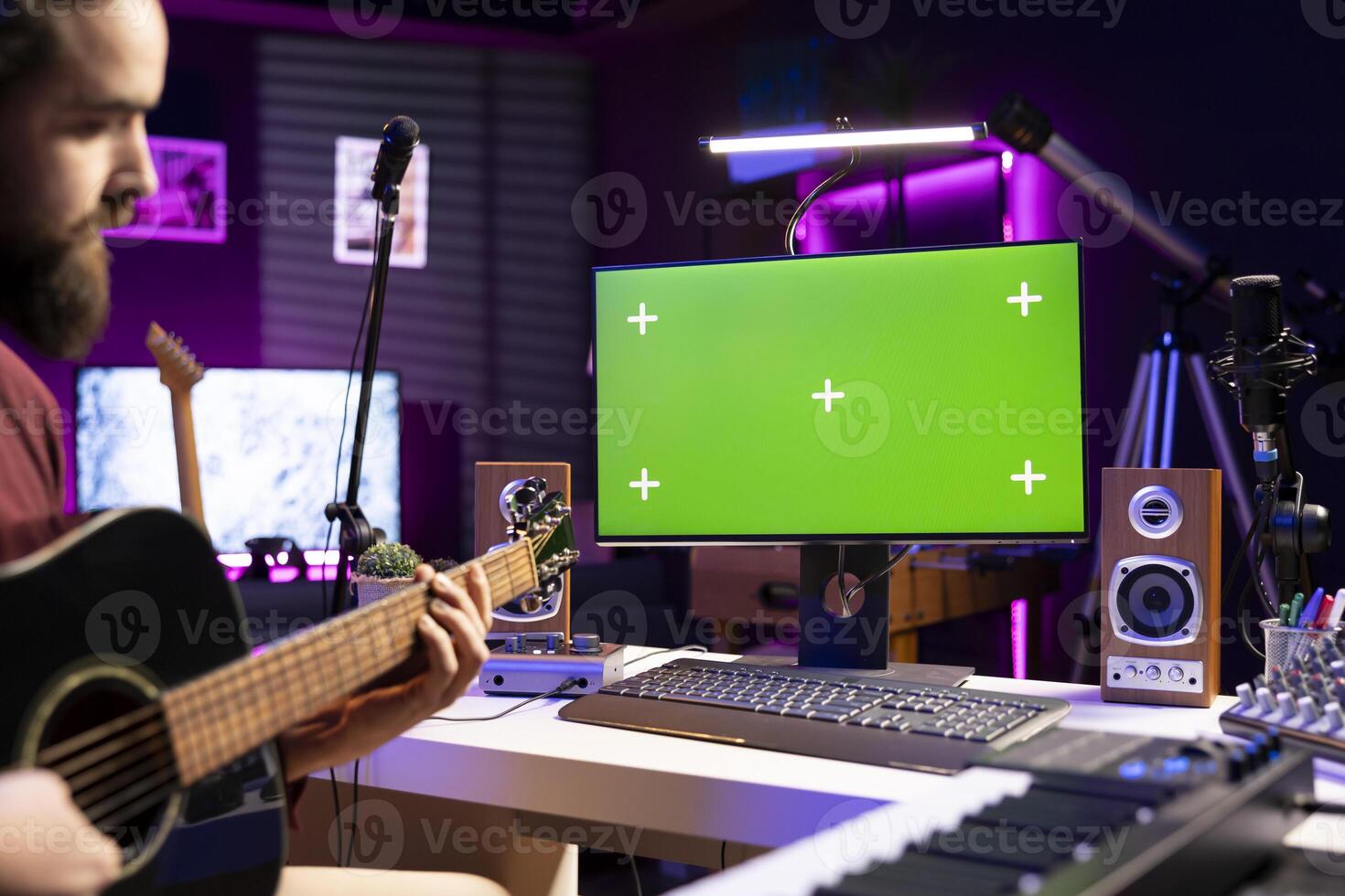 Musician playing acoustic guitar with online tutorials on greenscreen pc, watching videos for musical rehearsal in home studio. Sound engineer learning new string accords on instrument. photo