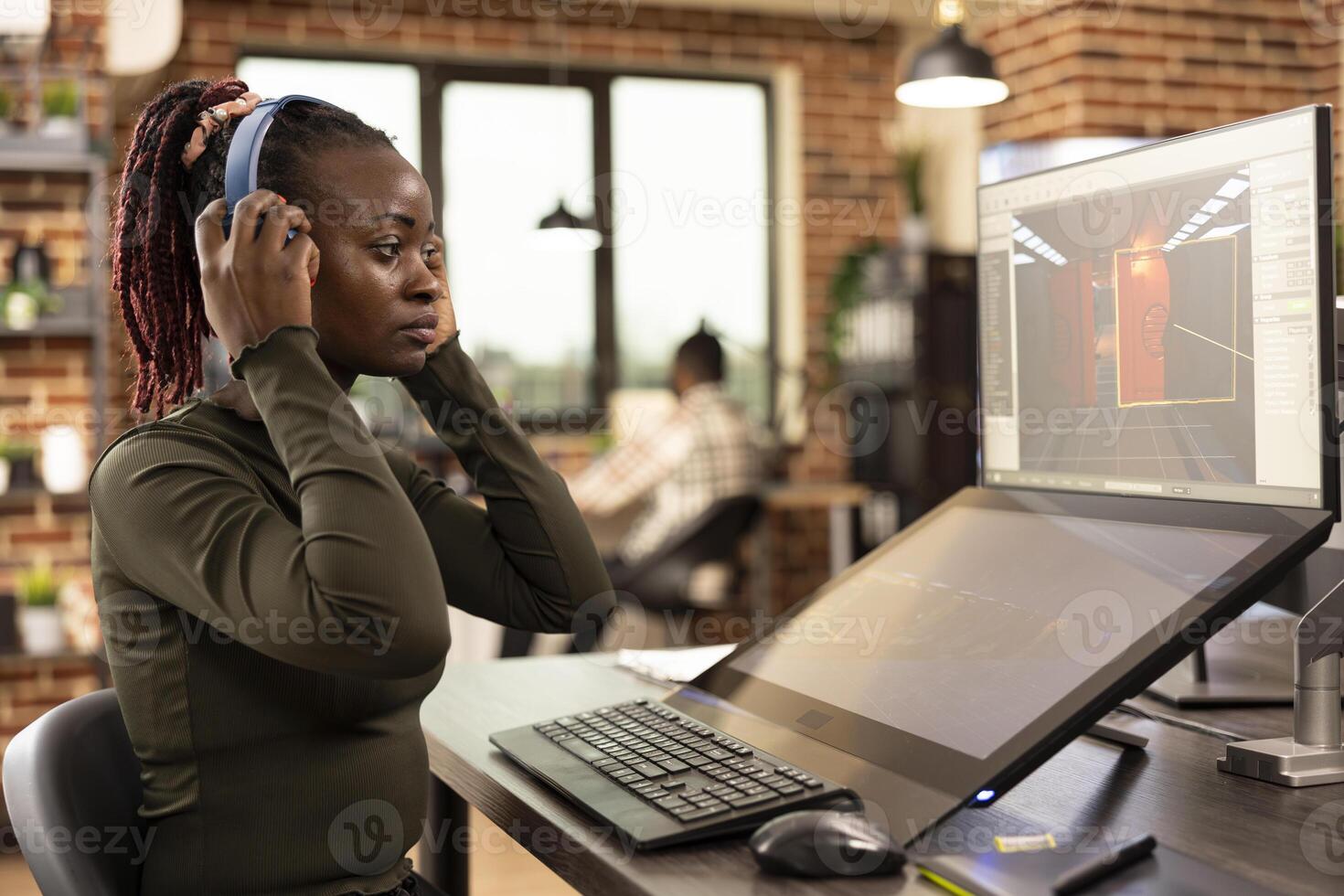 African American designer refining projects on digital monitors enhancing visuals in modern creative workspace. Black woman focused on editing and 3D modeling working across multiple screens. photo