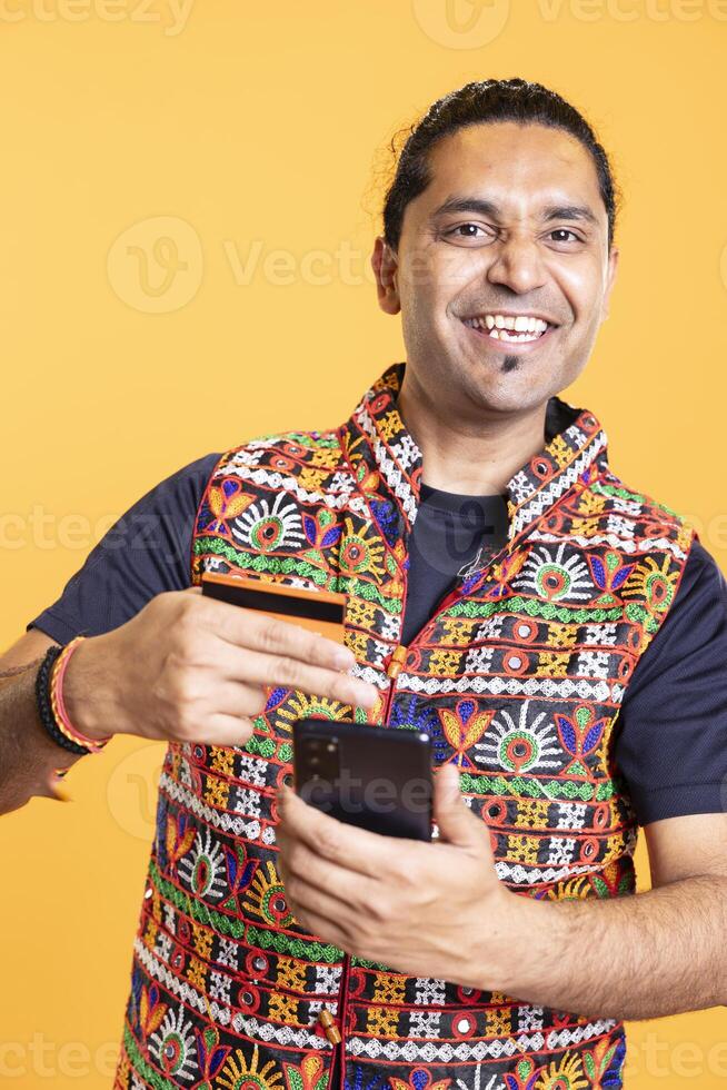 Portrait of happy man grinning while adding payment method on phone website, delighted to take advantage of promotions. Ecstatic person excited to do internet shopping on smartphone, studio backdrop photo