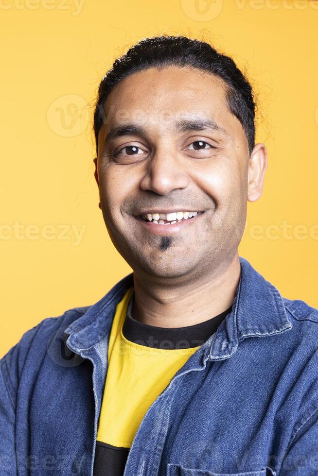 Portrait of jolly indian man smiling and posing with arms crossed standing against studio background. Joyous upbeat male person in casual clothing showcases positive emotions. photo