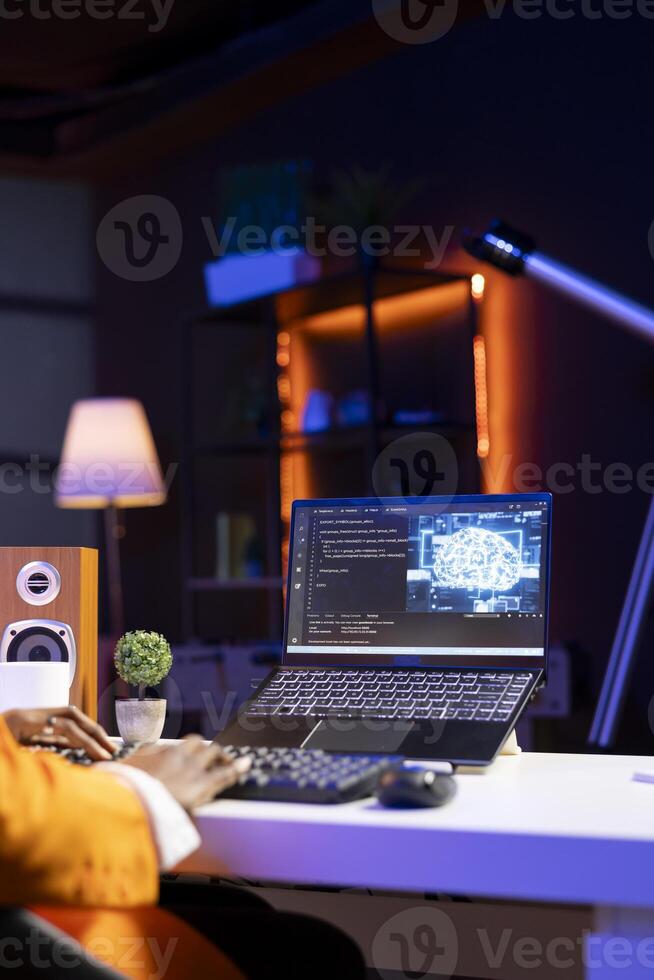 Computer scientist using laptop, updating artificial intelligence neural networks, writing binary code scripts. Young remote employee working from home uses notebook, programming AI photo