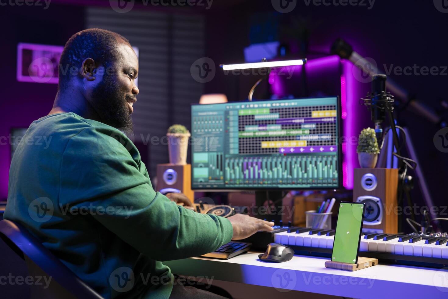 Composer musician mixing his tracks in pc software with an isolated smartphone screen, working on launching new music. Artist operating on mixing console, producing and editing sounds. photo