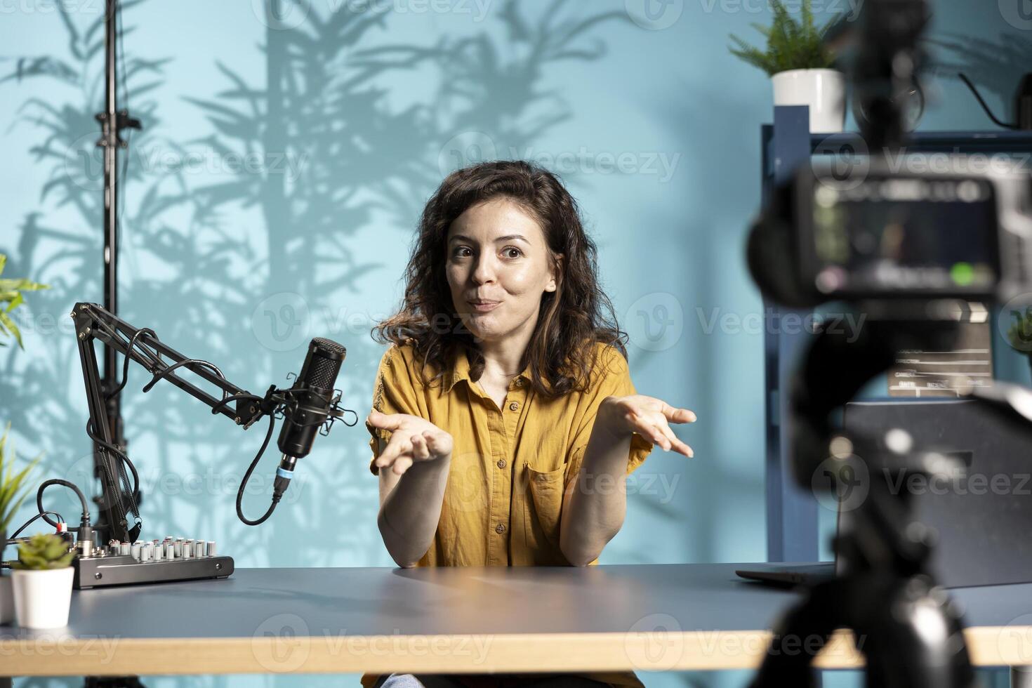 Happy influencer talking in professional microphone in brightly lit studio, filming internet production. Cheerful woman uses content creation recording mic in apartment photo