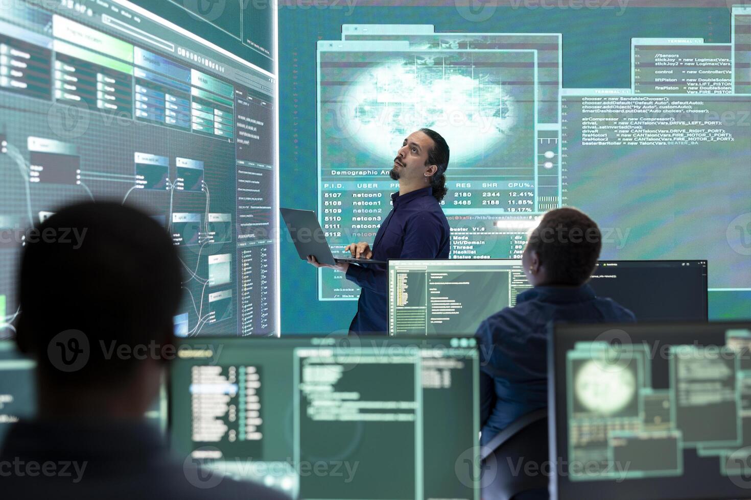 Professional hacker using ransomware and phishing tactics to compromise networks and gather intelligence for national security during cyberwarfare. Governmental spyware on big screen. photo