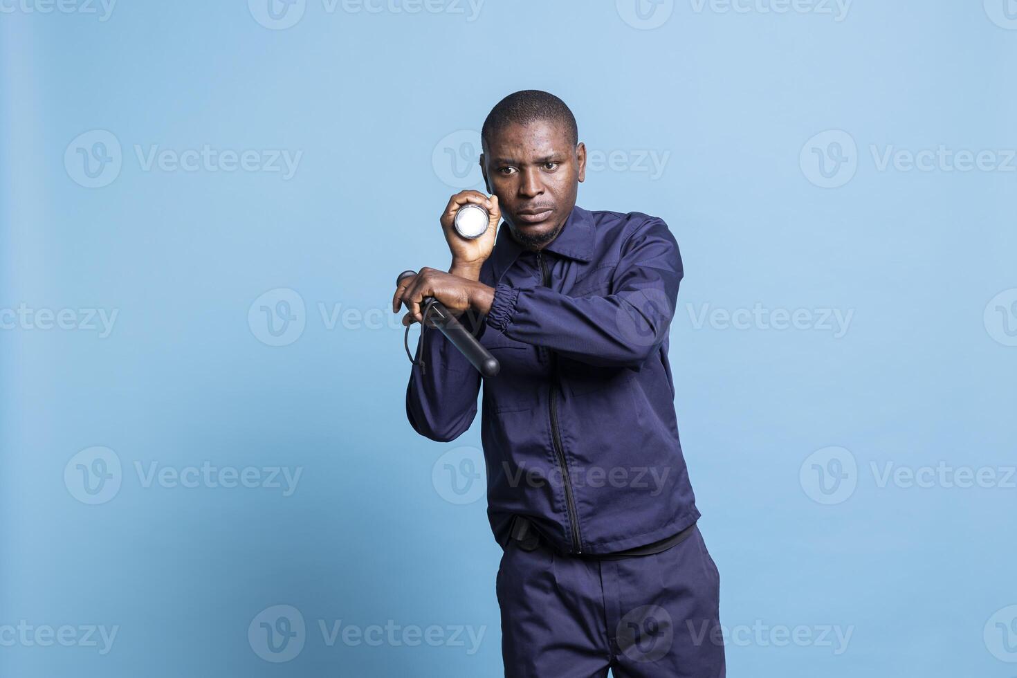 Security agent patrolling the perimeter with a lantern and baton, working on protecting and safeguarding the premises in the dark. Skilled trained guard inspecting the area, alertness. photo