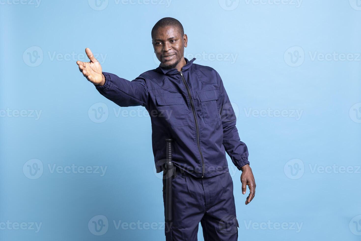 African american man works as a security officer at a mall, restricting the access and pointing people in another direction. Bodyguard is guiding persons to left or right in studio. photo