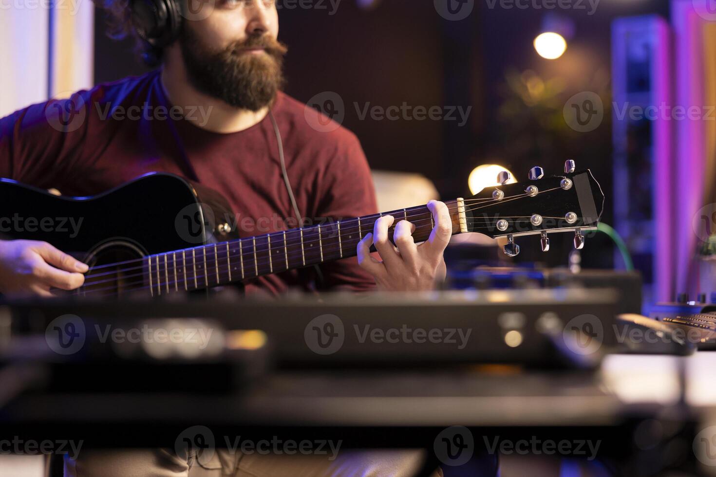 Musician playing guitar and uses mixing gear to create new music, looking at daw software interface on computer. Producer recording soundtracks with electronic equipment, acoustical engineering. photo