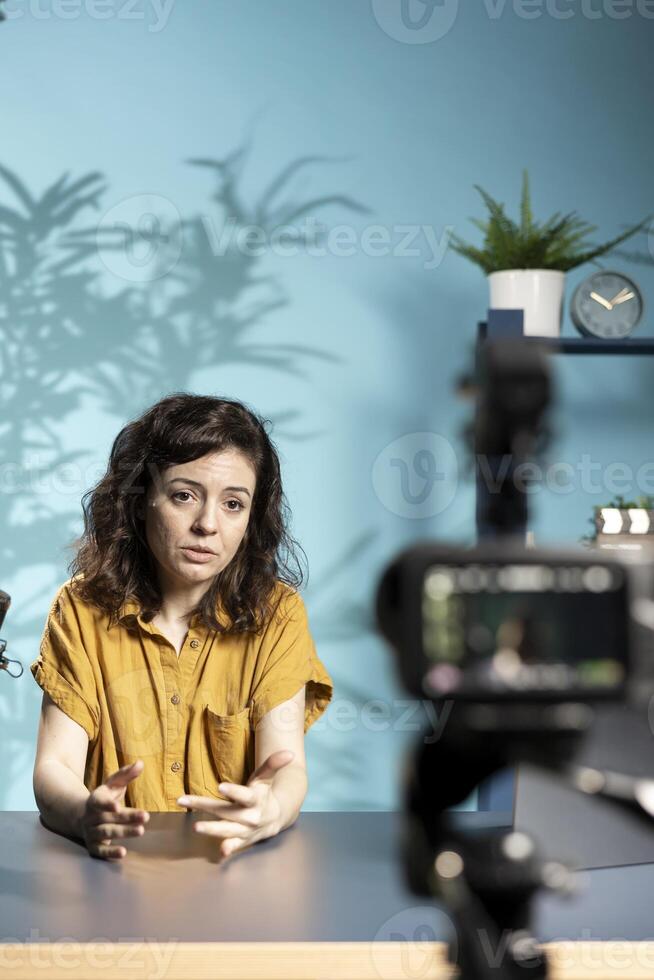 Depressed woman talking with audience about importance of mental health. Upset influencer sulking while hosting internet show, using high tech quality mic recording with professional camera photo