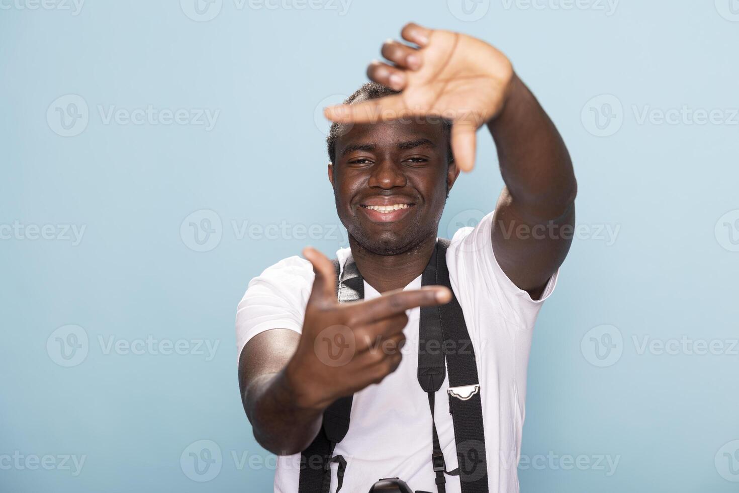 African American male filmmaker framing his shot with his fingers, forming a rectangle shape instead of using the viewfinder. Black man doing a signature hand gesture of photographers in studio. photo