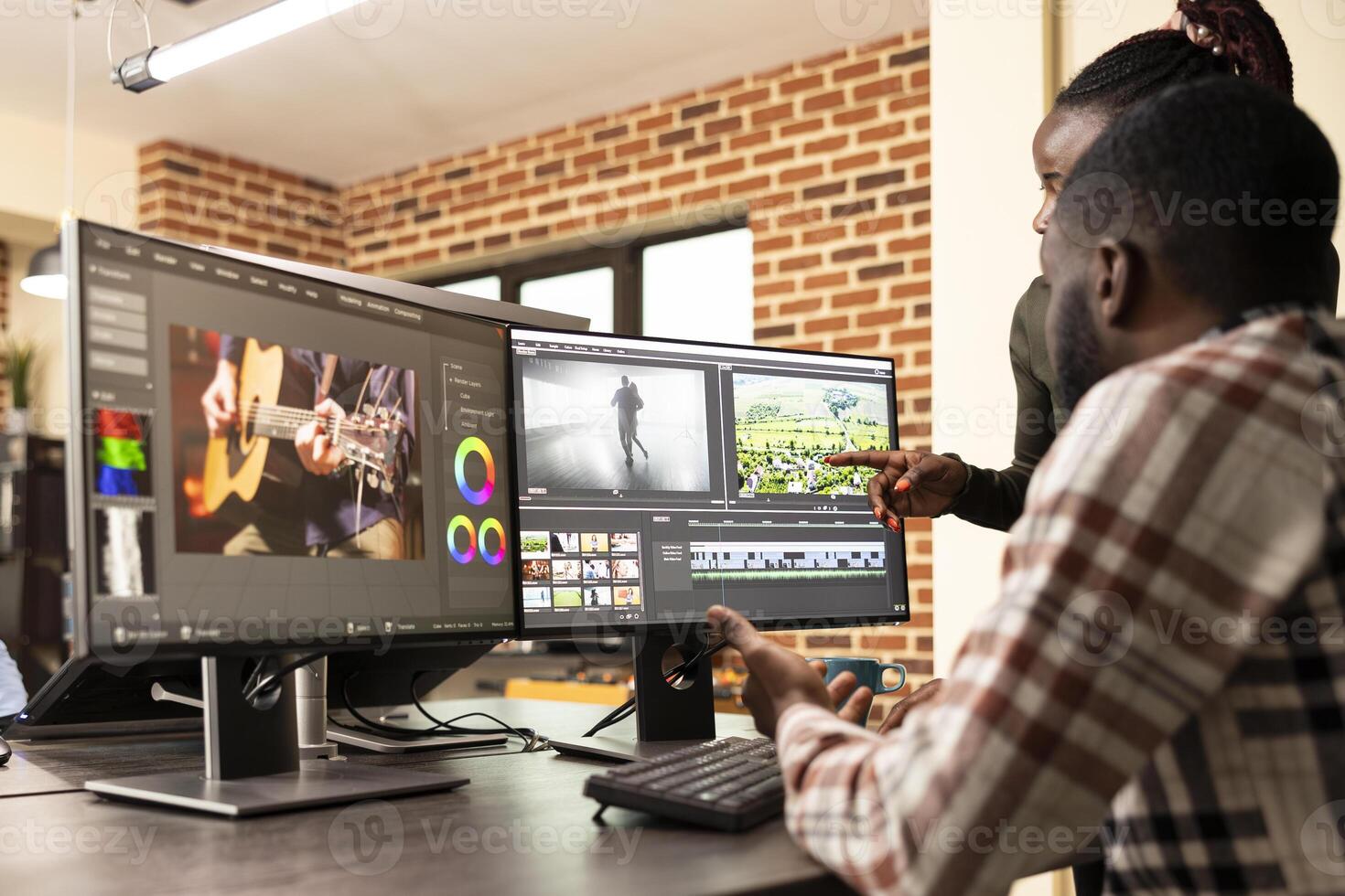 Professional male editor refining frames as coworker provides visual improvement support. Black man improving film quality at multi monitor workstation with assistance from female creative manager. photo