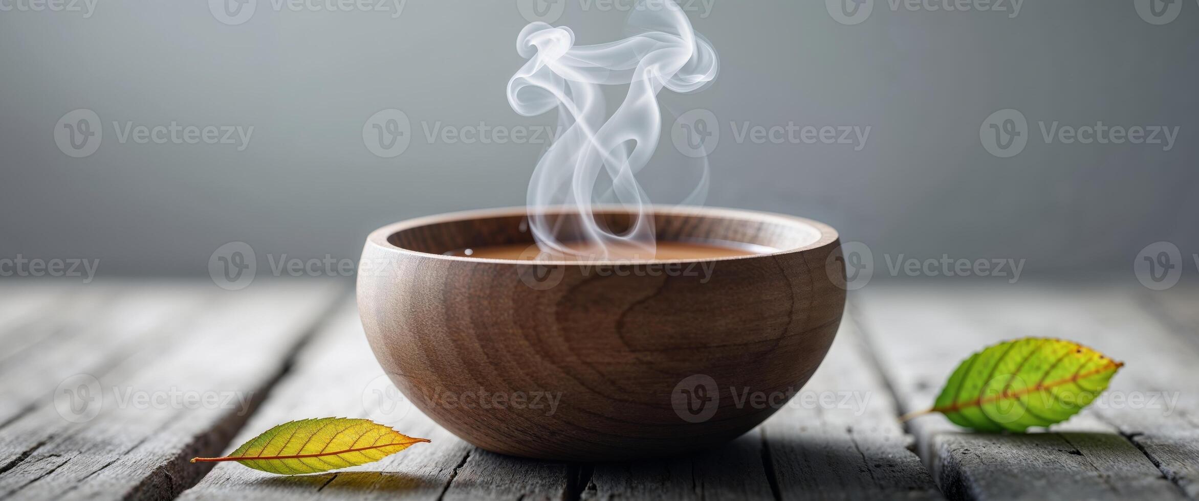 A cup of hot tea with leaves on a wooden table photo