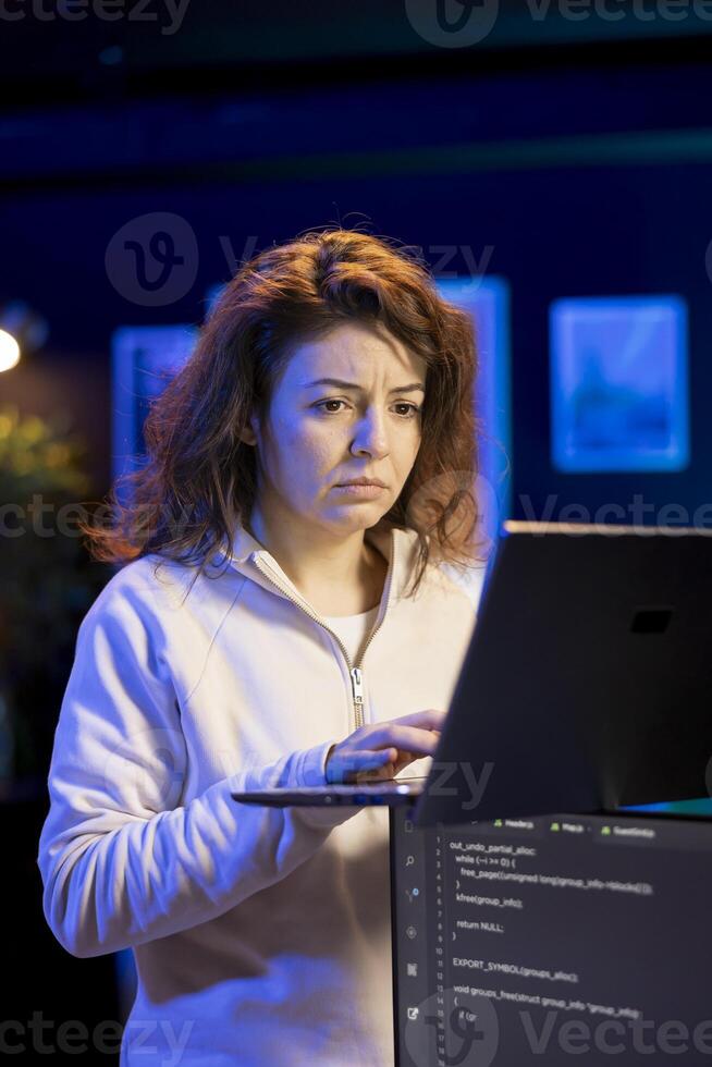 Programmer walking in apartment designing and developing software applications using laptop. IT expert standing in living room, implementing and maintaining company systems photo
