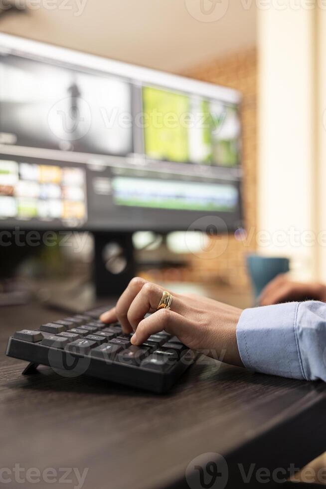 Closeup of a person using computer keyboard at office desk during their editing session. Selective focus on female hands seated at workstation, typing and improving film montage visual quality. photo