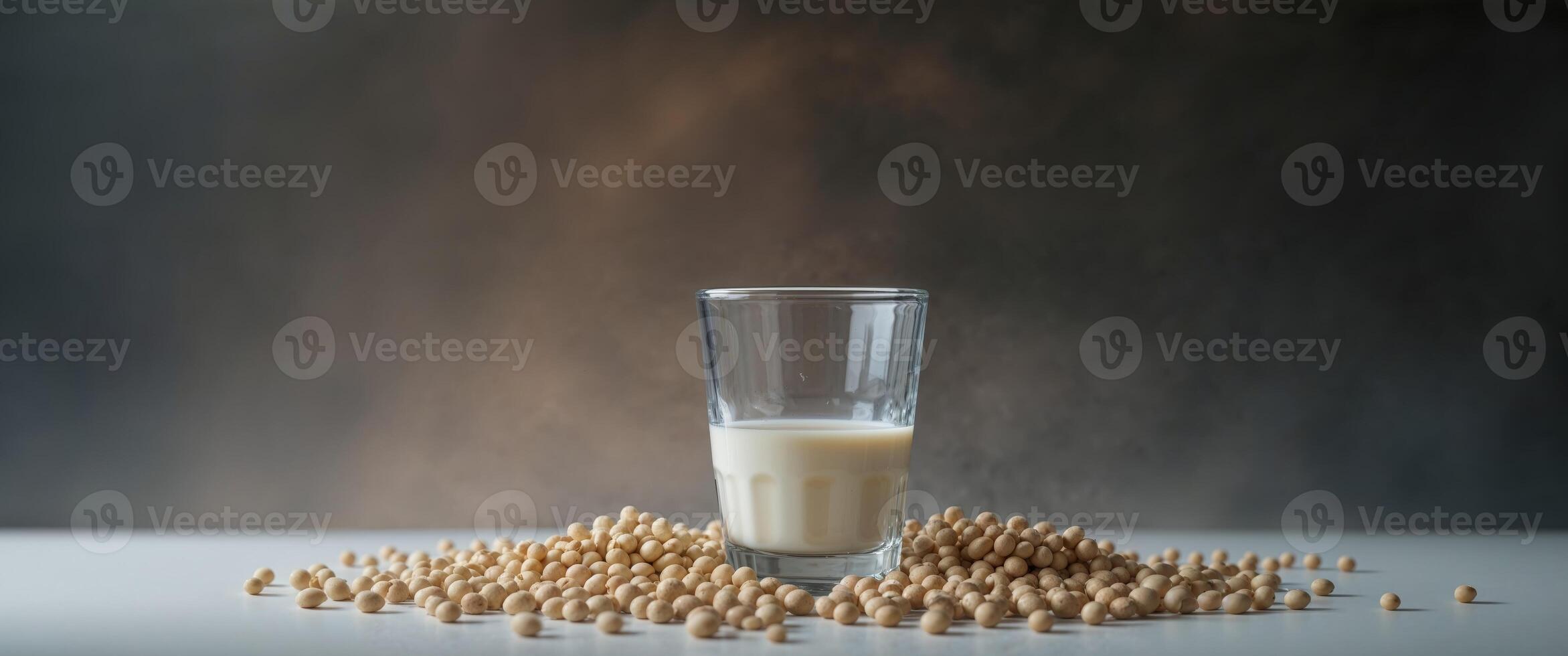 Fresh soy milk in a glass surrounded by soybeans on a dark background. photo
