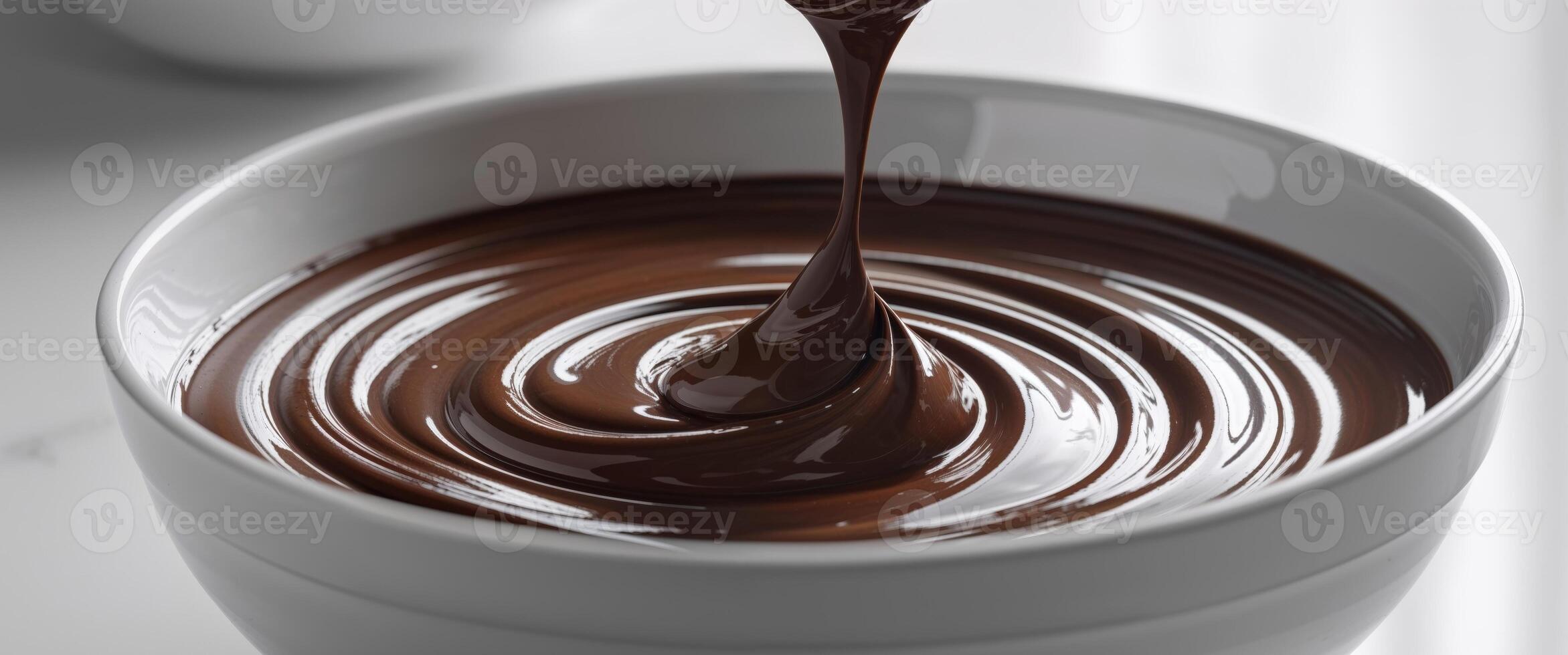 Melting rich chocolate being stirred in a bowl creating smooth texture and glossy appearance. photo