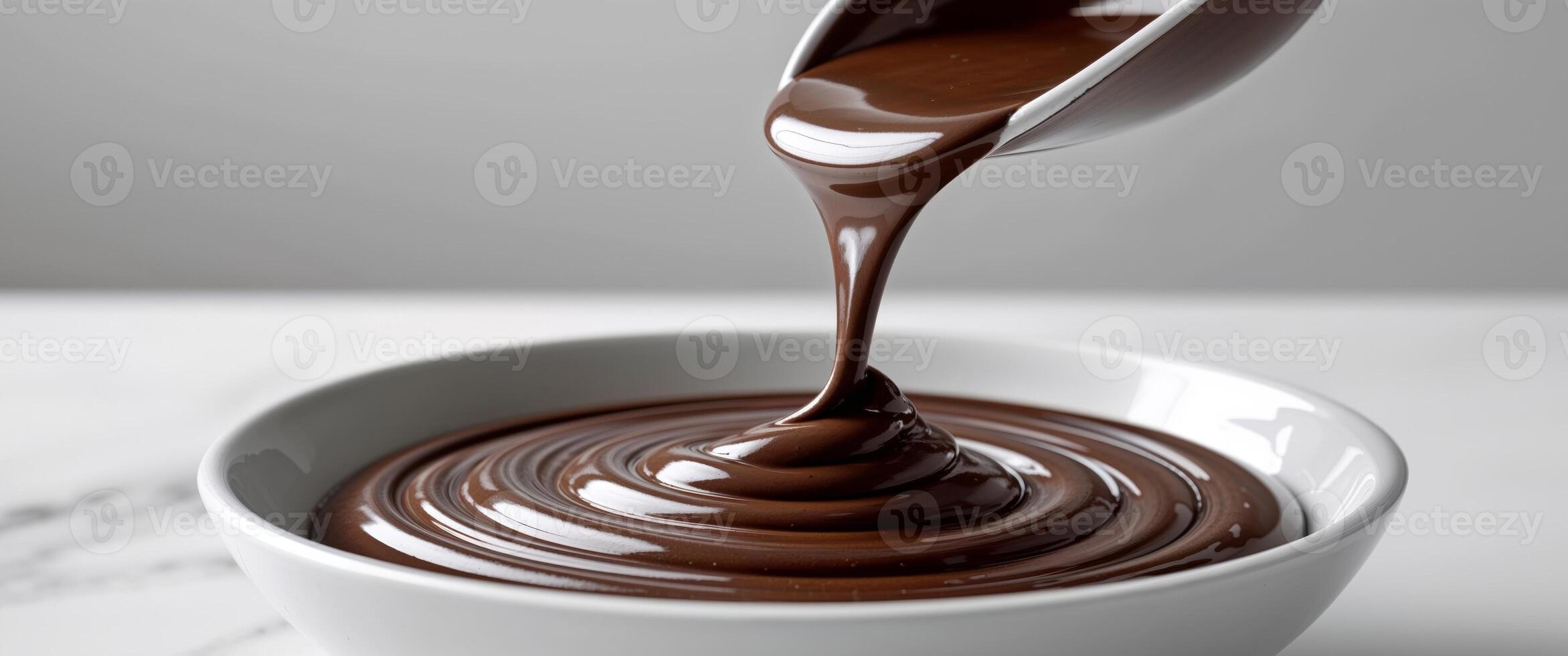 Melting rich chocolate being stirred in a bowl creating smooth texture and glossy appearance photo