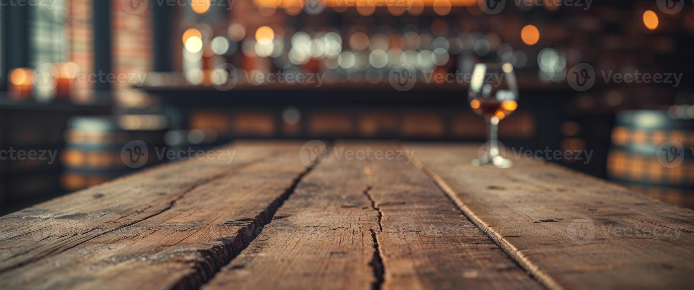 A glass of whiskey on a wooden table in front of a bar photo