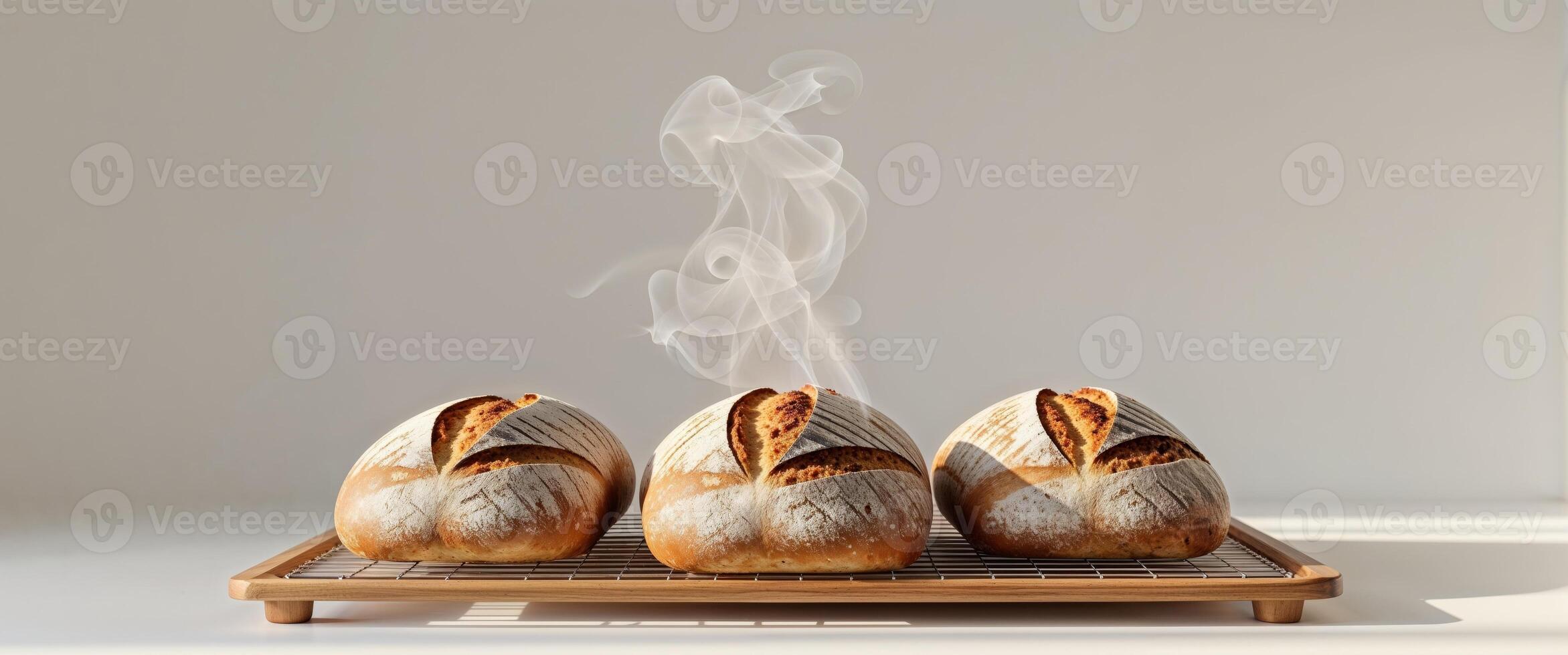 Three loaves of bread on a tray with smoke coming out of them photo