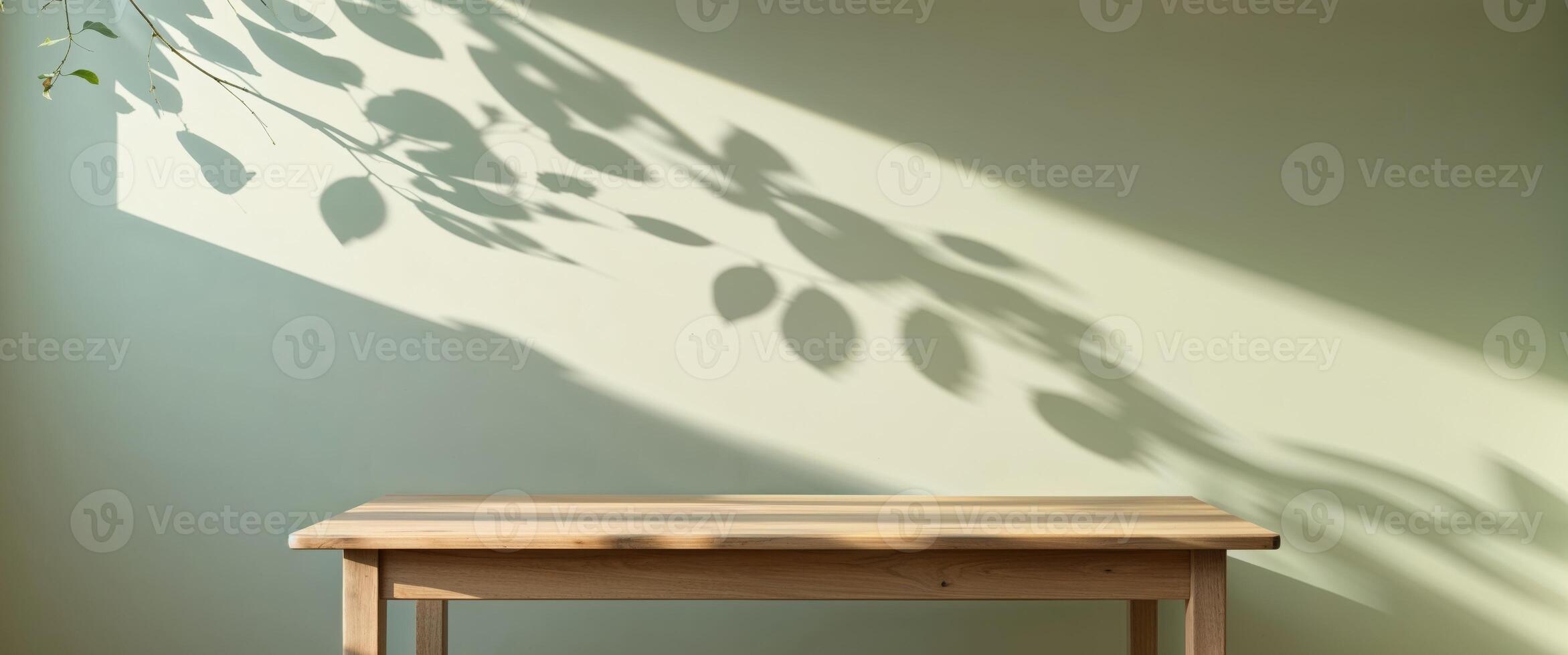 Wooden table with leaf shadows on light green wall photo