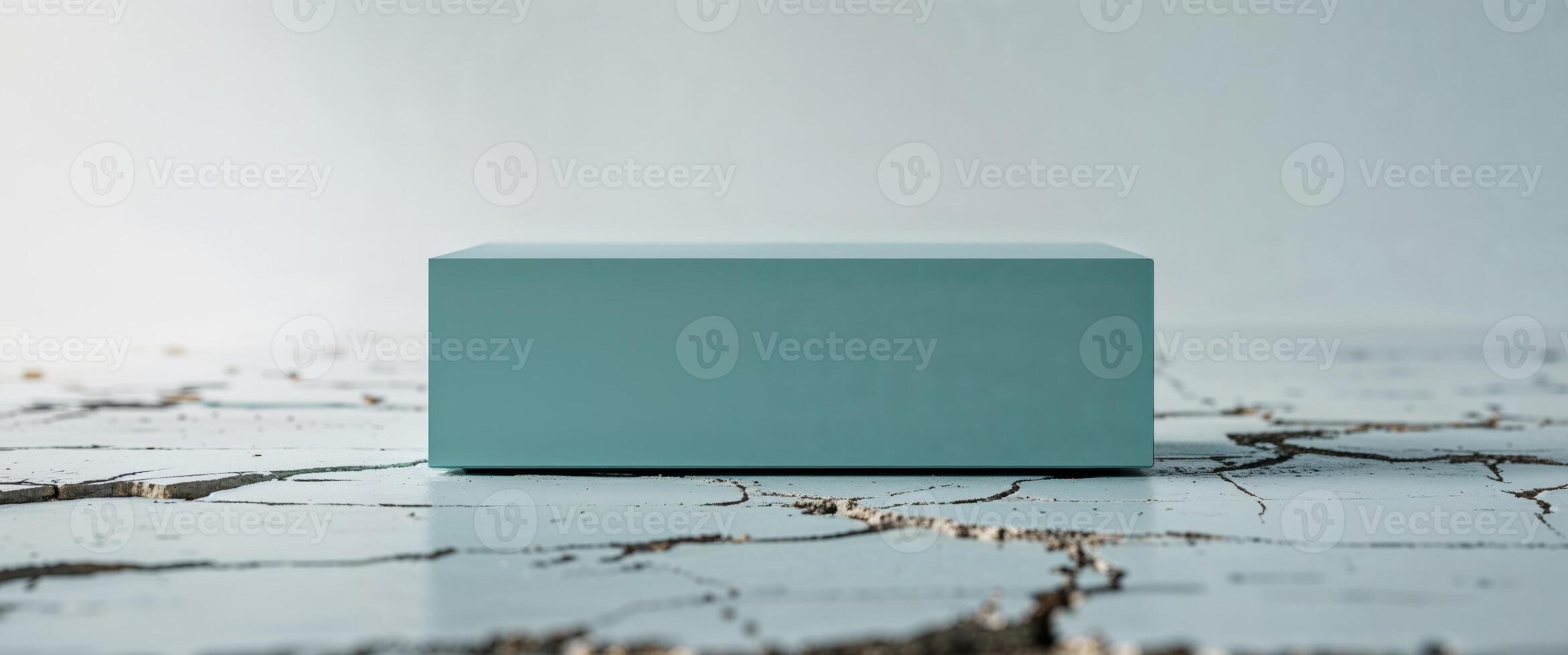 Rectangular teal object resting on cracked white surface photo