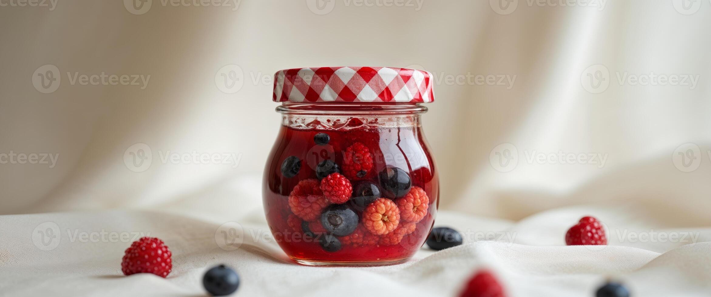 A jar of raspberry jam with berries on a white cloth photo