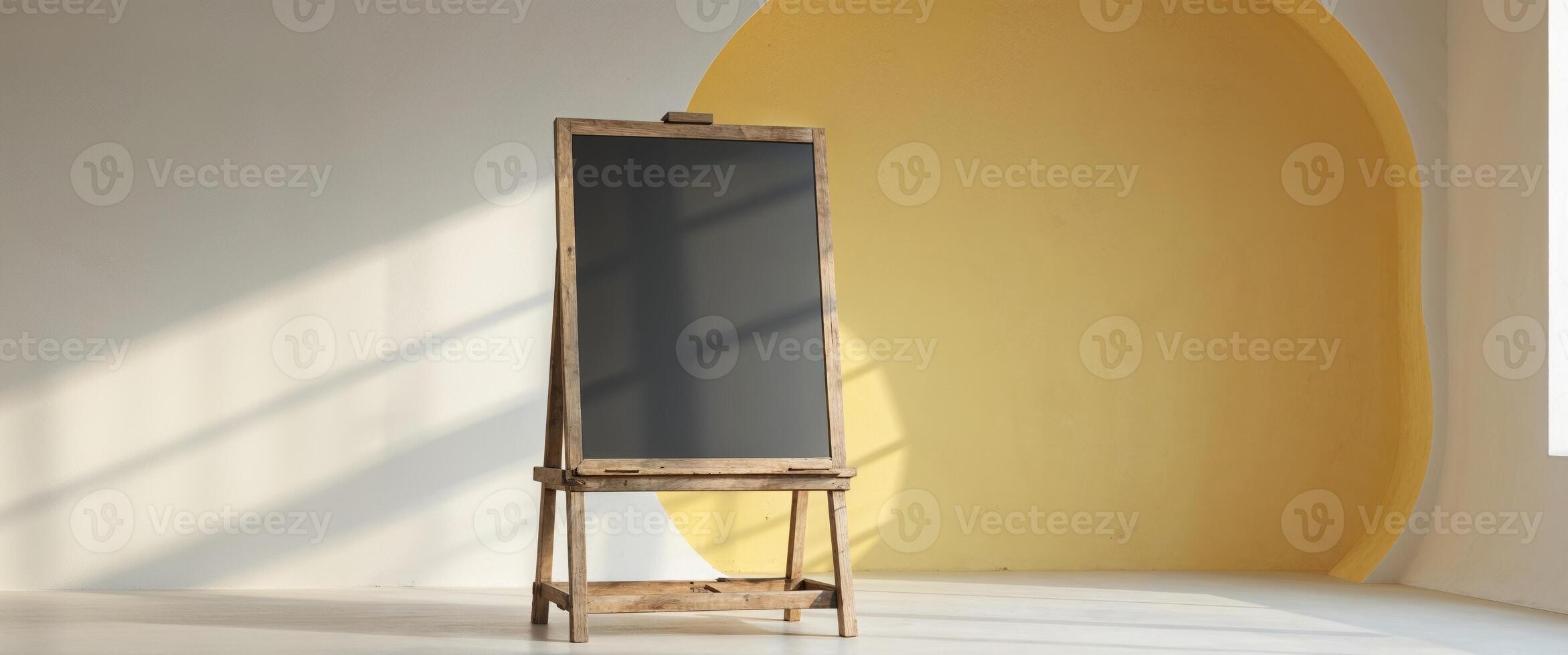 A wooden easel with a chalkboard in front of a yellow wall photo