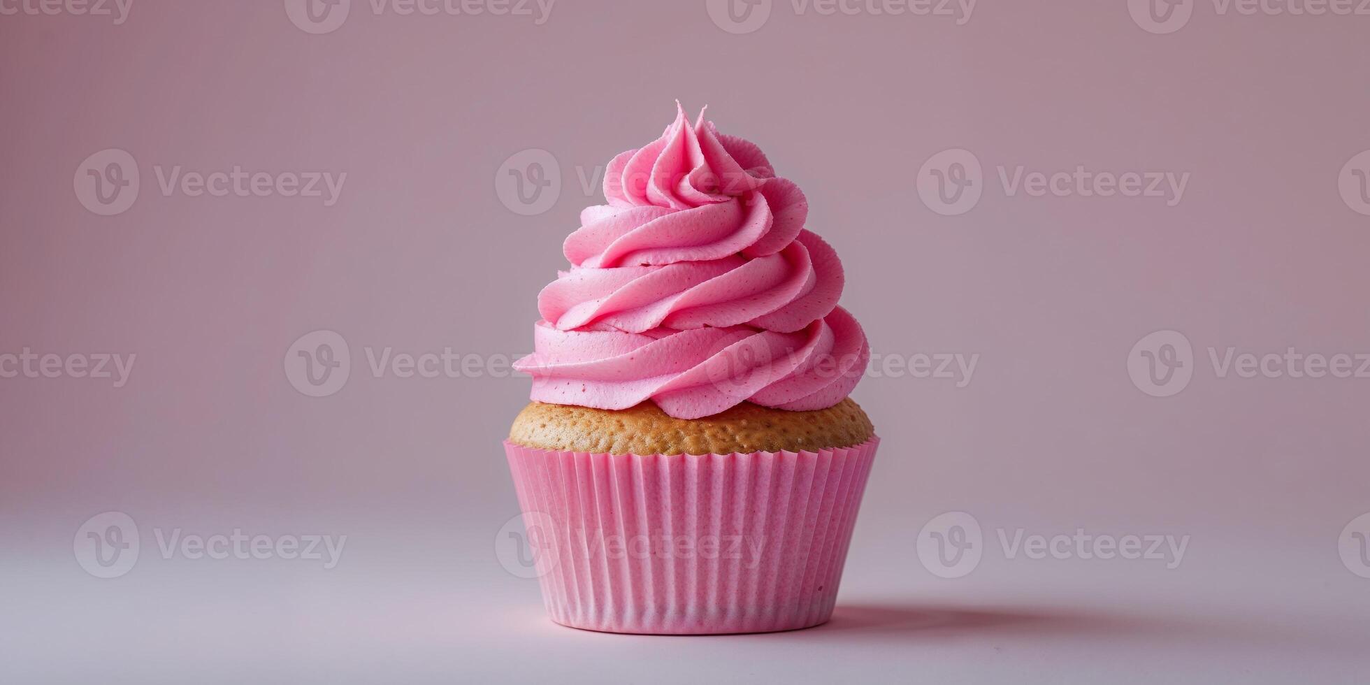 A single cupcake with pink frosting in a pink wrapper on a pink background in a studio shot photo