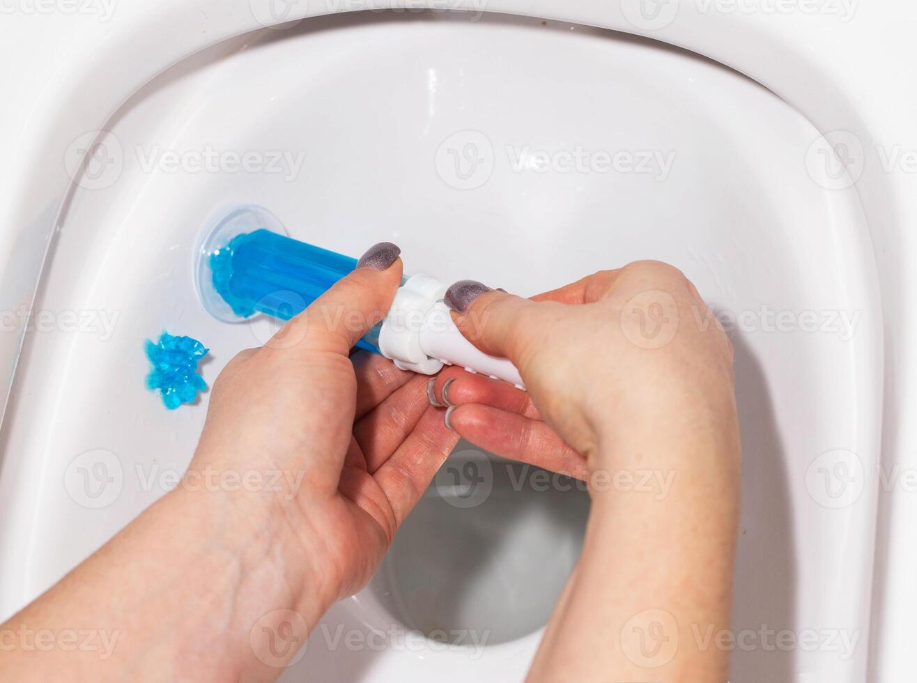 A syringe with ocean-scented gel for cleaning and disinfecting the toilet in a hand against the background of a toilet. Antibacterial effect photo