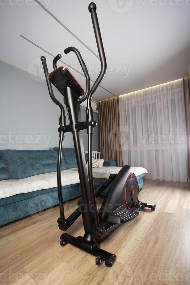 New modern elliptical trainer at home in the exercise room photo
