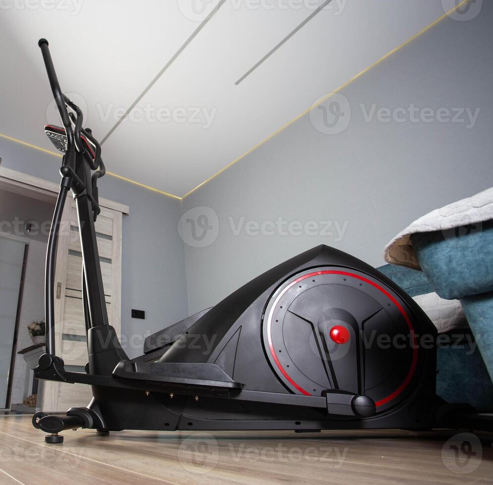 Modern Elliptical Trainer in the Room at Home. Concept of Exercising at Home, fitness. Copy space for text photo