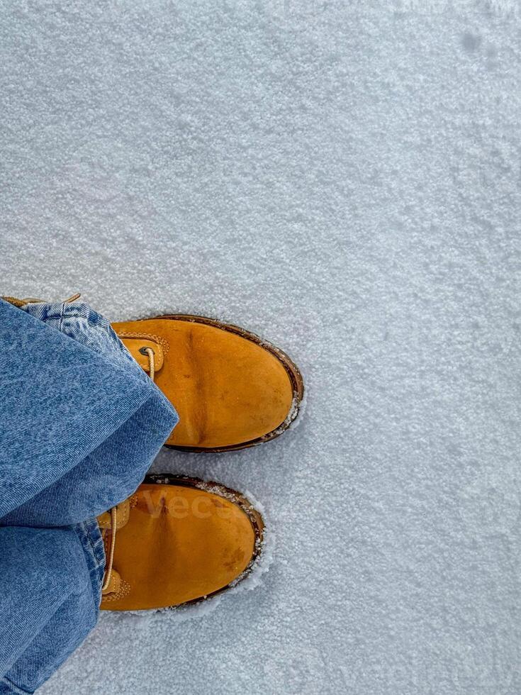 Snowy ground view with yellow boots in a winter landscape photo
