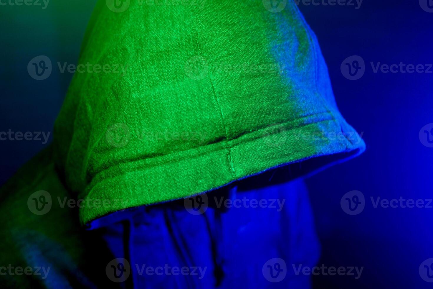 Mysterious figure shrouded in green and blue light at nighttime photo
