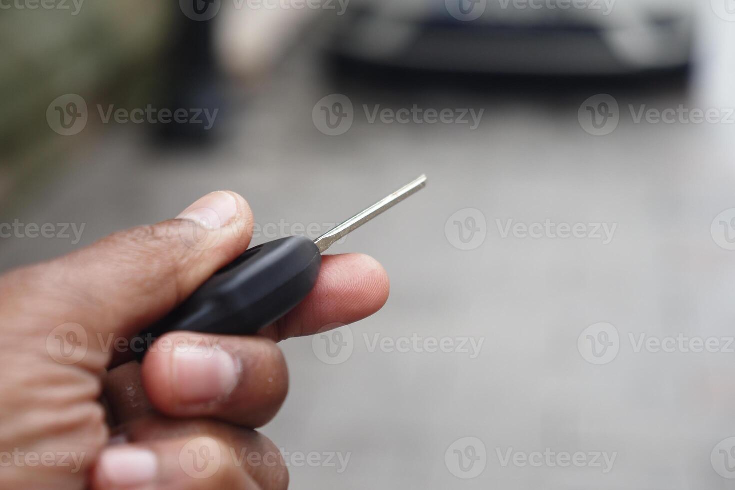 Hand holding a car key while standing on a street photo