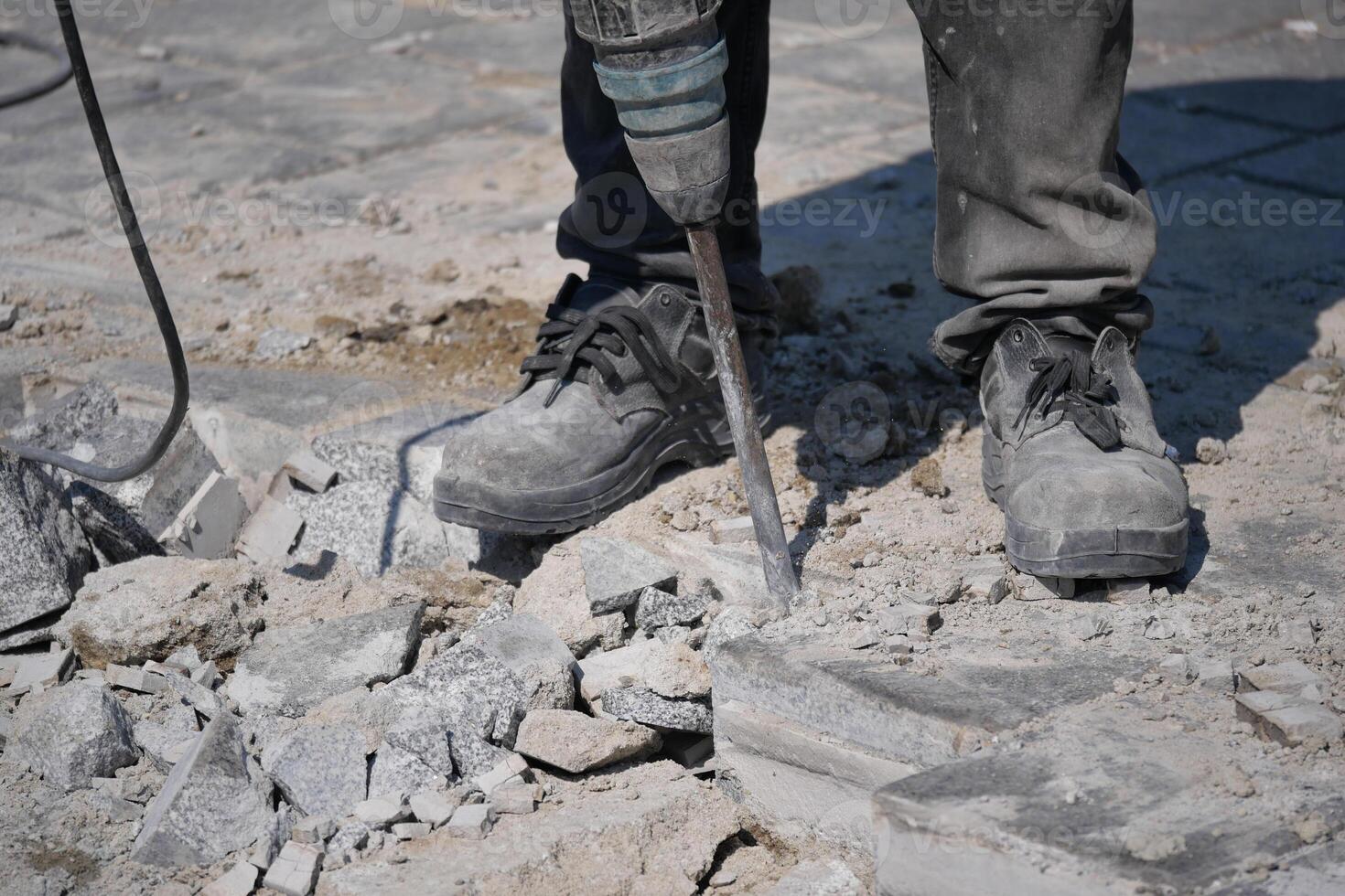 Worker using pneumatic tool to break concrete at construction site photo