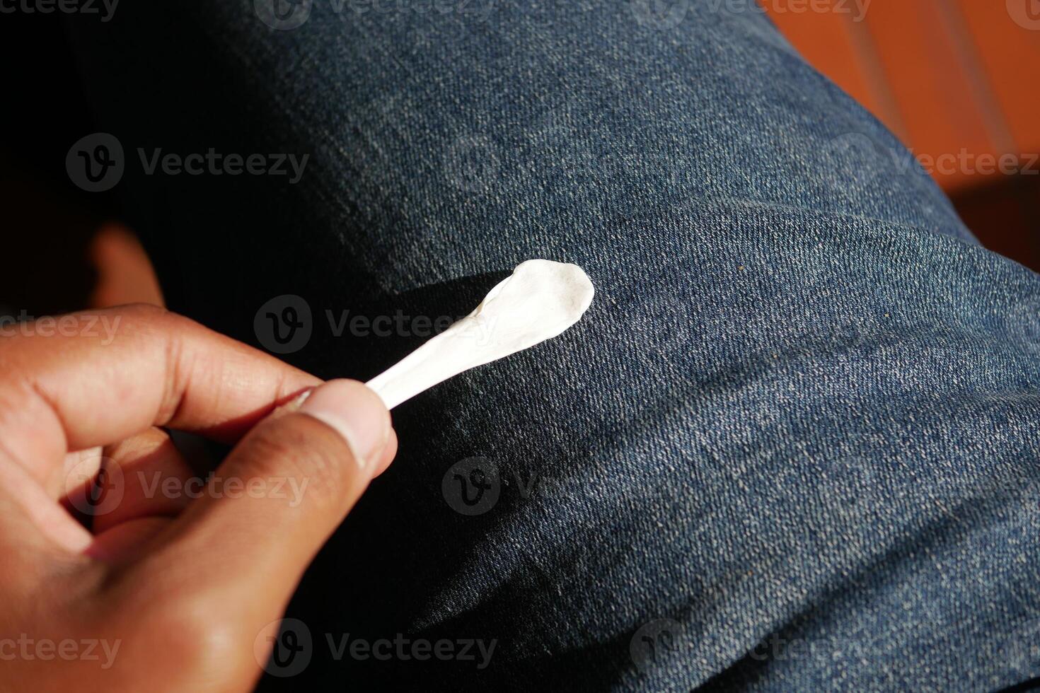 Close-up of hand holding chewing gum on denim jeans photo