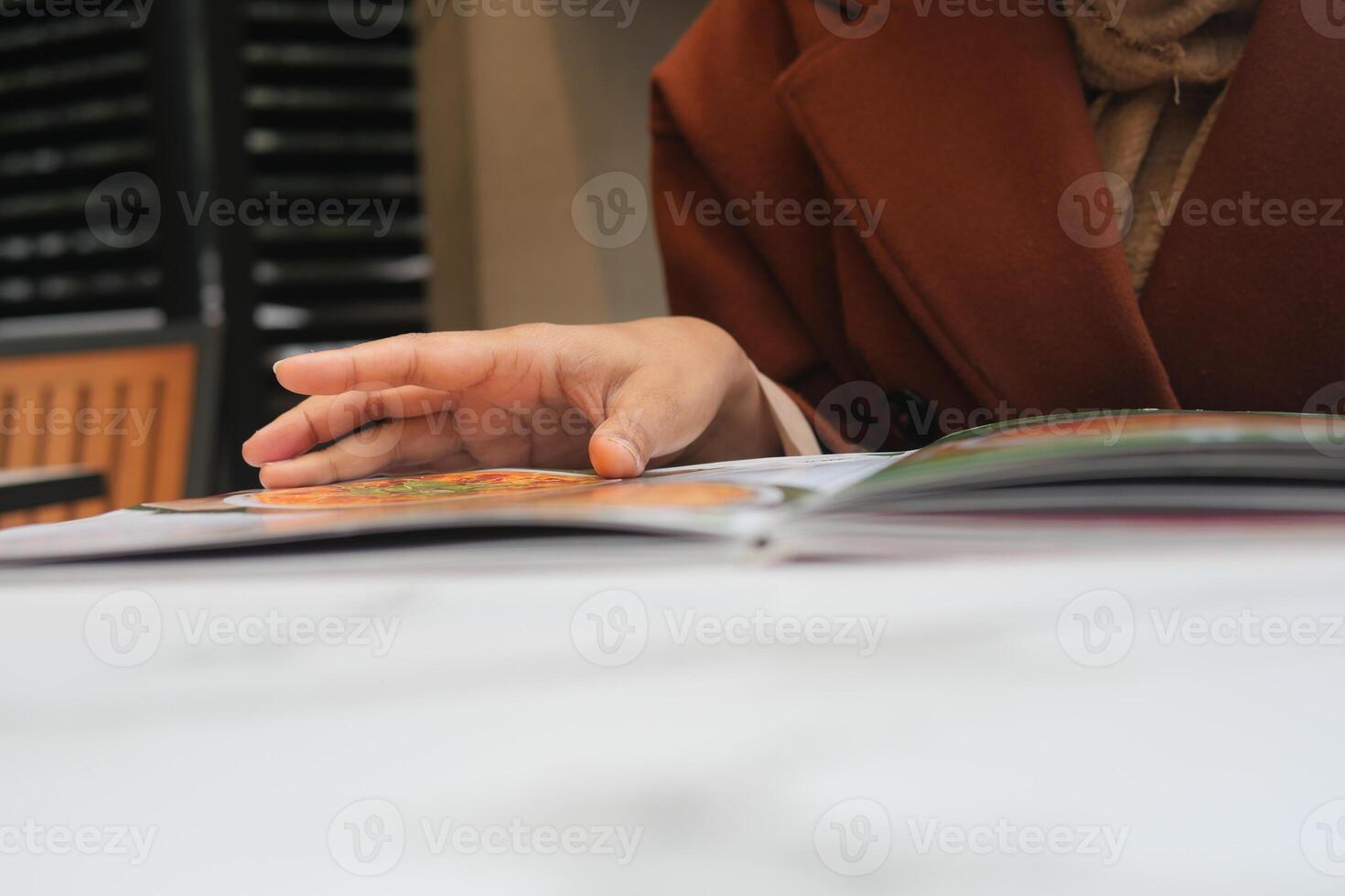 Hand flipping through a menu at a cozy cafe in autumn photo