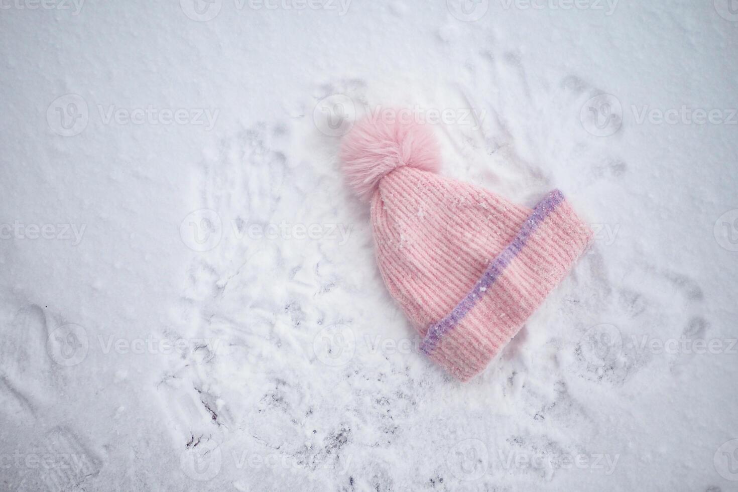 Winter hat resting on freshly fallen snow with handprints around photo