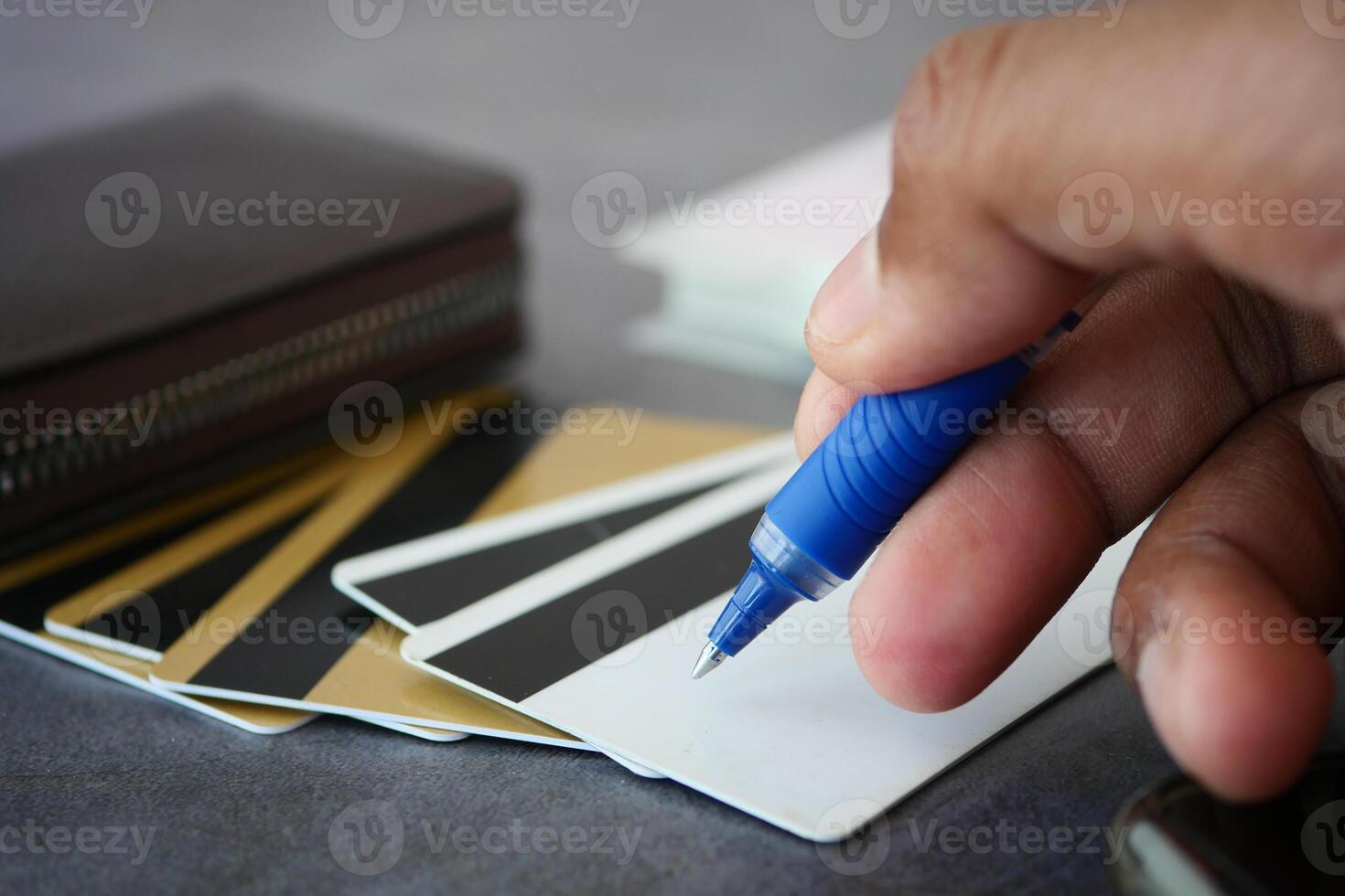 Writing on a blank card while surrounded by various cards and a wallet photo