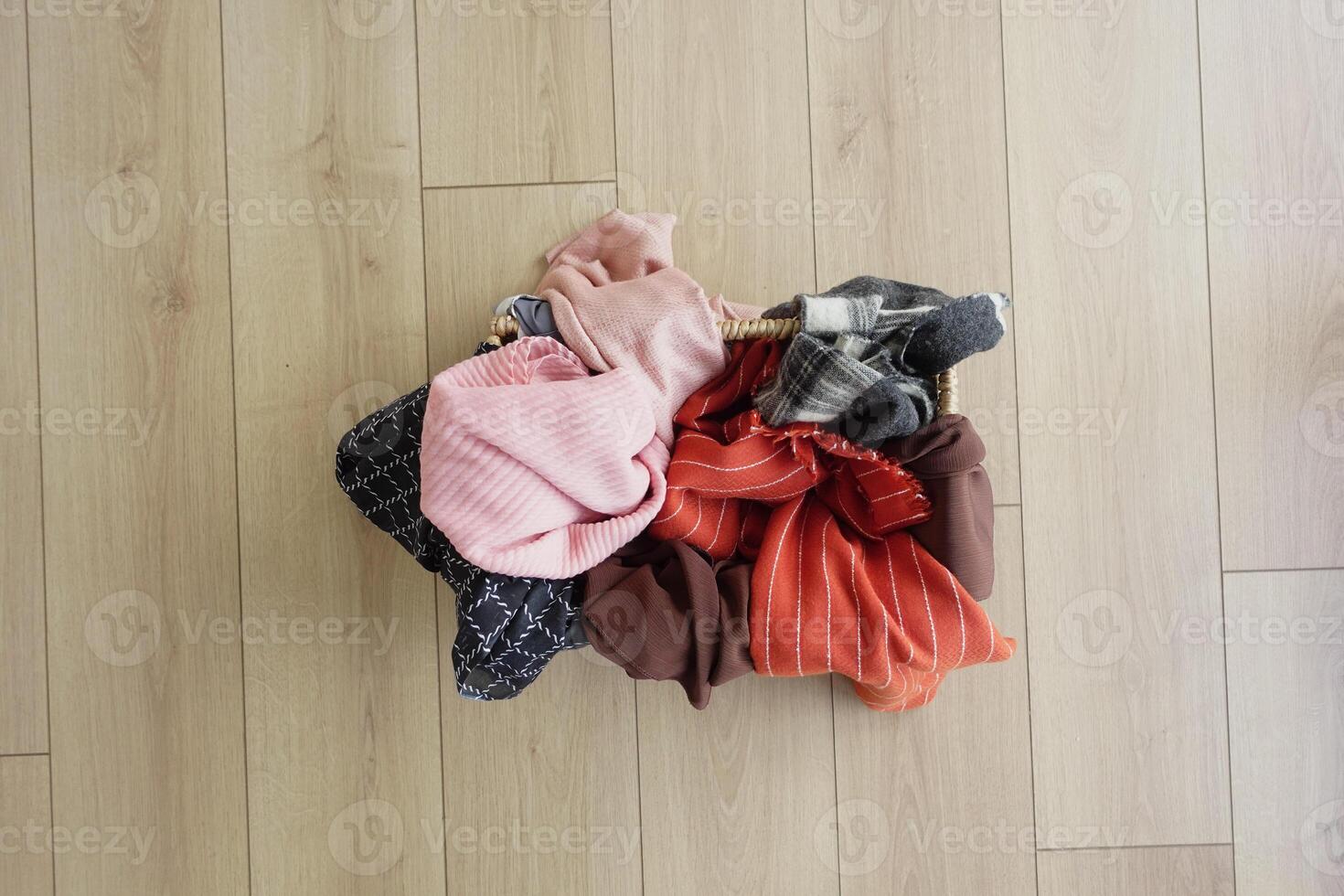 Colorful assortment of clothes in a woven basket on wooden floor photo